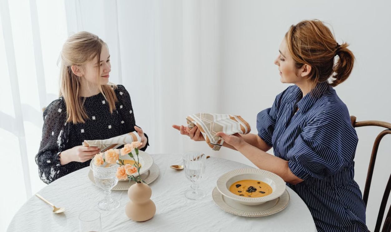 A mother and daughter share a meal, focusing on table etiquette and bonding over lunch.