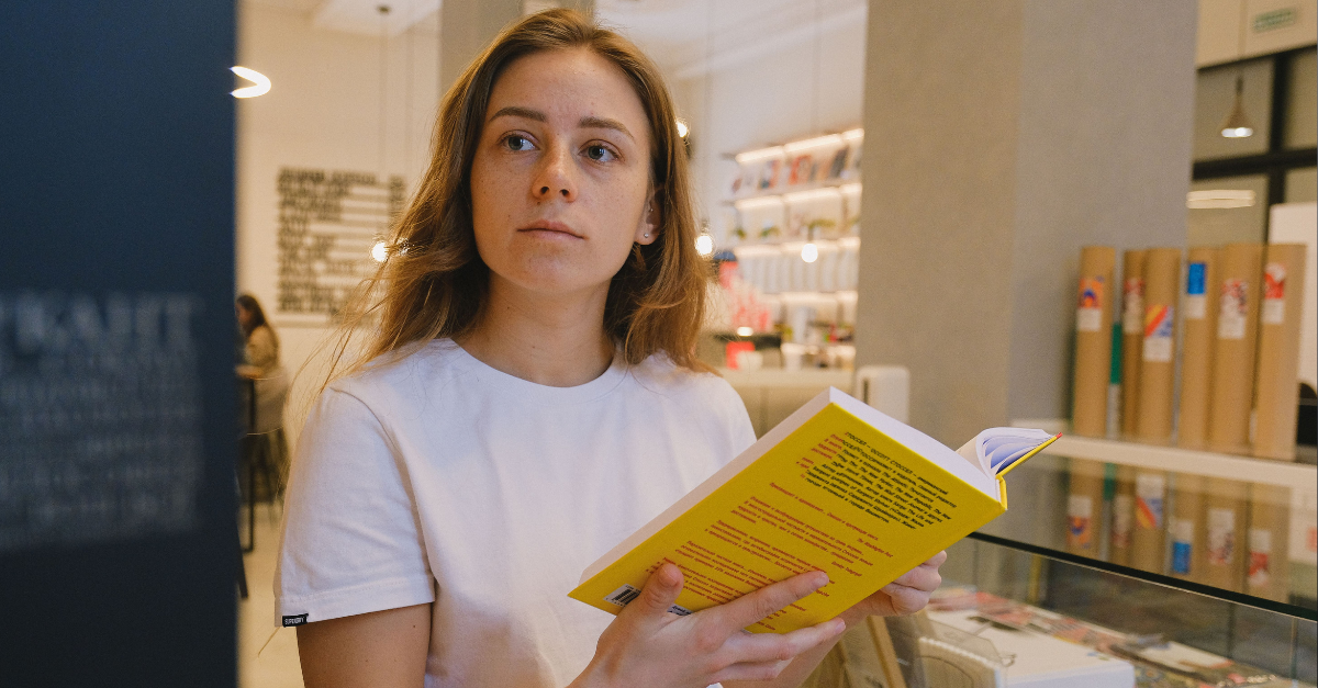 a-woman-in-white-t-shirt-holding-a-yellow-book