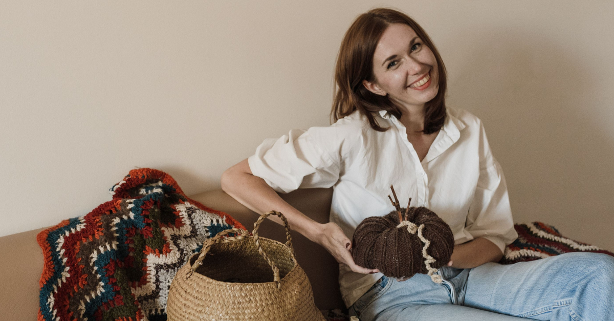 a-smiling-woman-sitting-on-couch-holding-yarn-roll