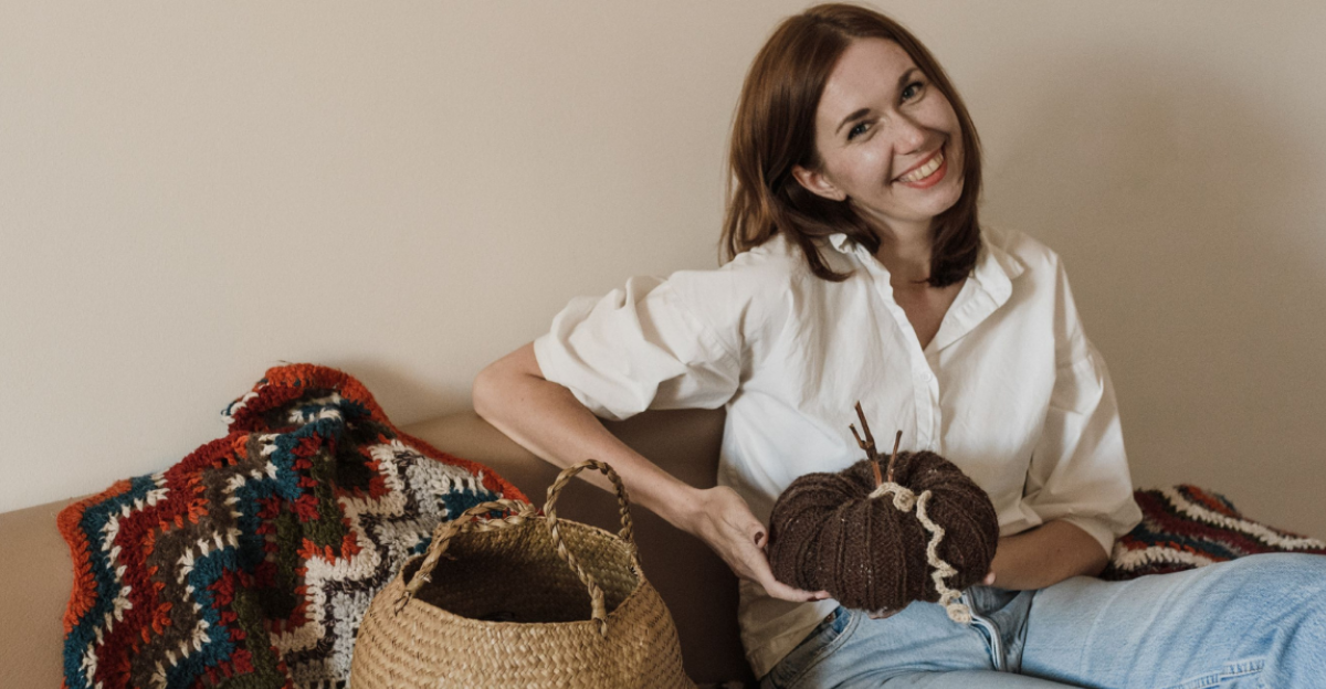 a-smiling-woman-sitting-on-couch-holding-yarn-roll