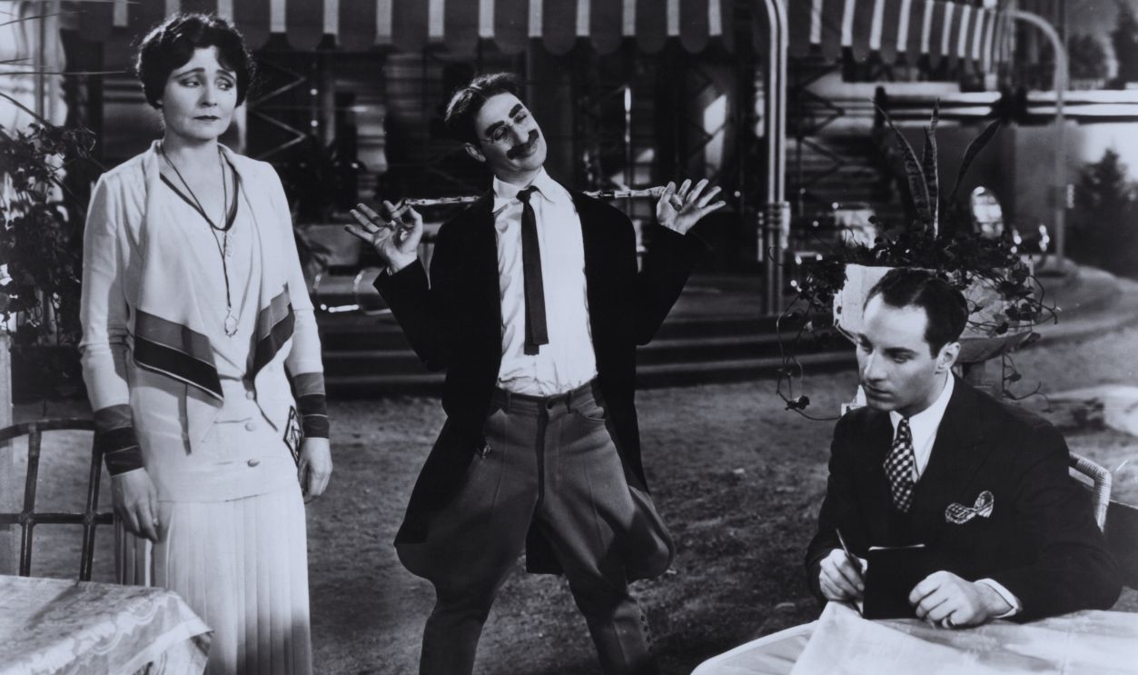 Gettyimages - 128010498, Margaret Dumont And Groucho Marx In 'The Cocoanuts' Margaret Dumont standing next to Groucho as he tries to entertain her and Zeppo Marx in a scene from the film 'The Cocoanuts', 1929.