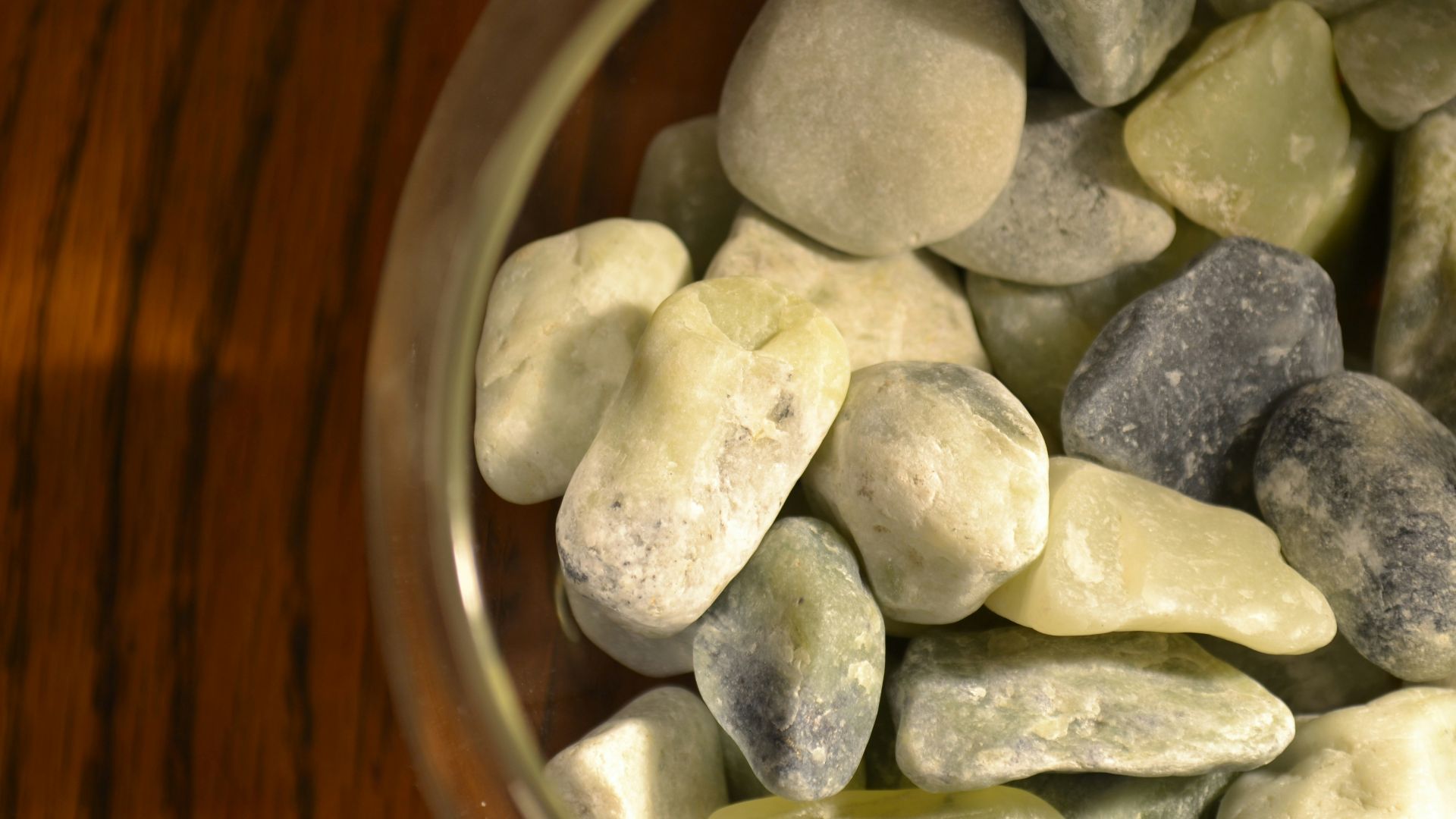 A glass bowl filled with rocks on top of a wooden table