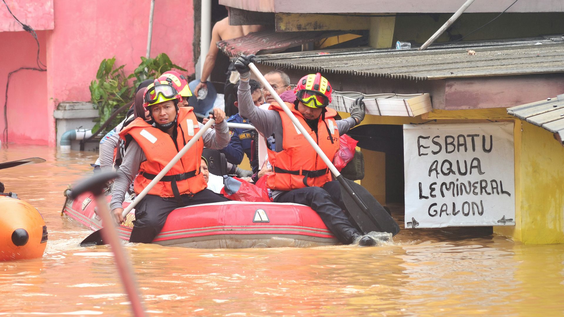 Rescue workers navigate floodwaters in a boat.