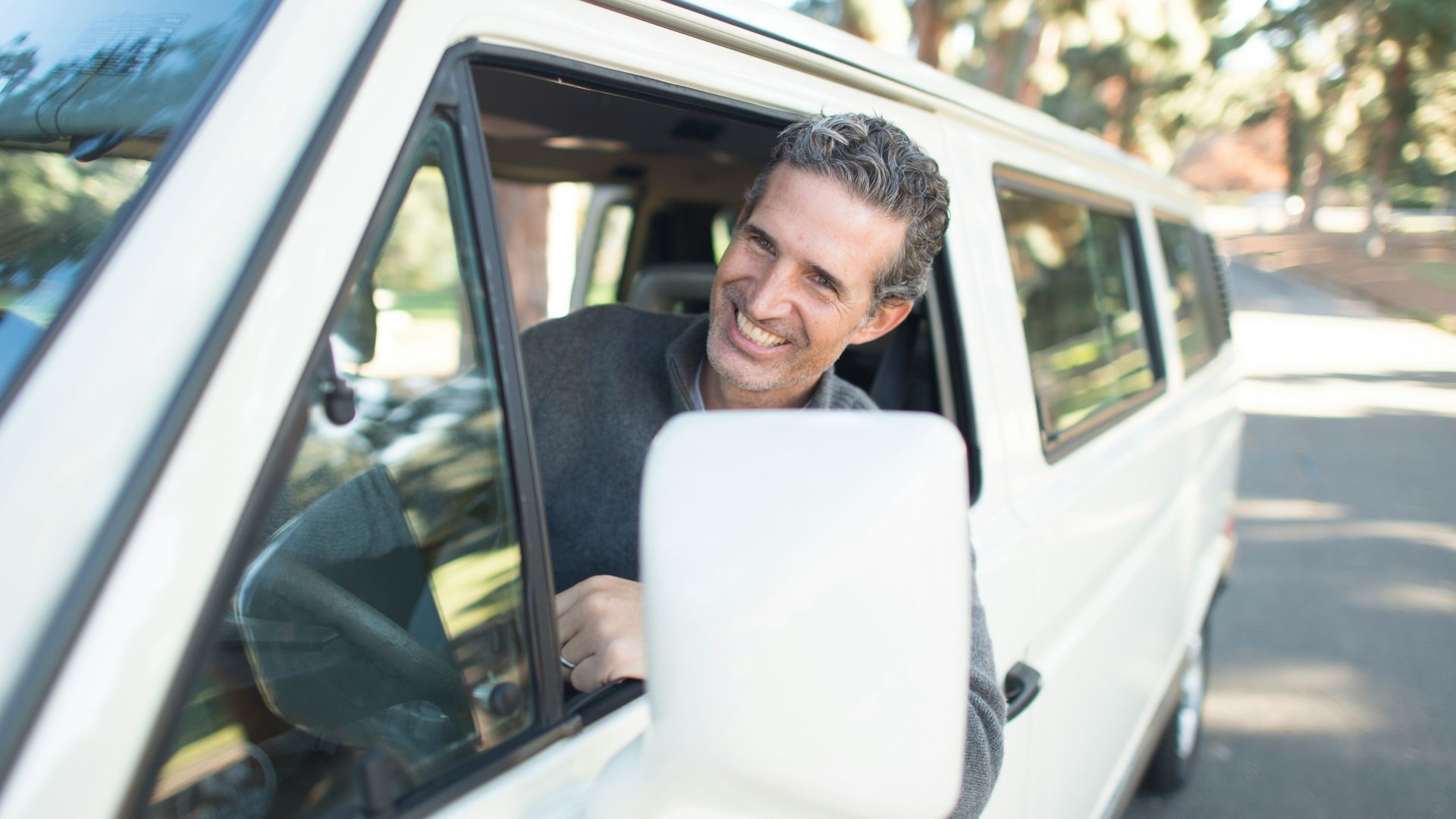 man in gray sweater leaning on van window
