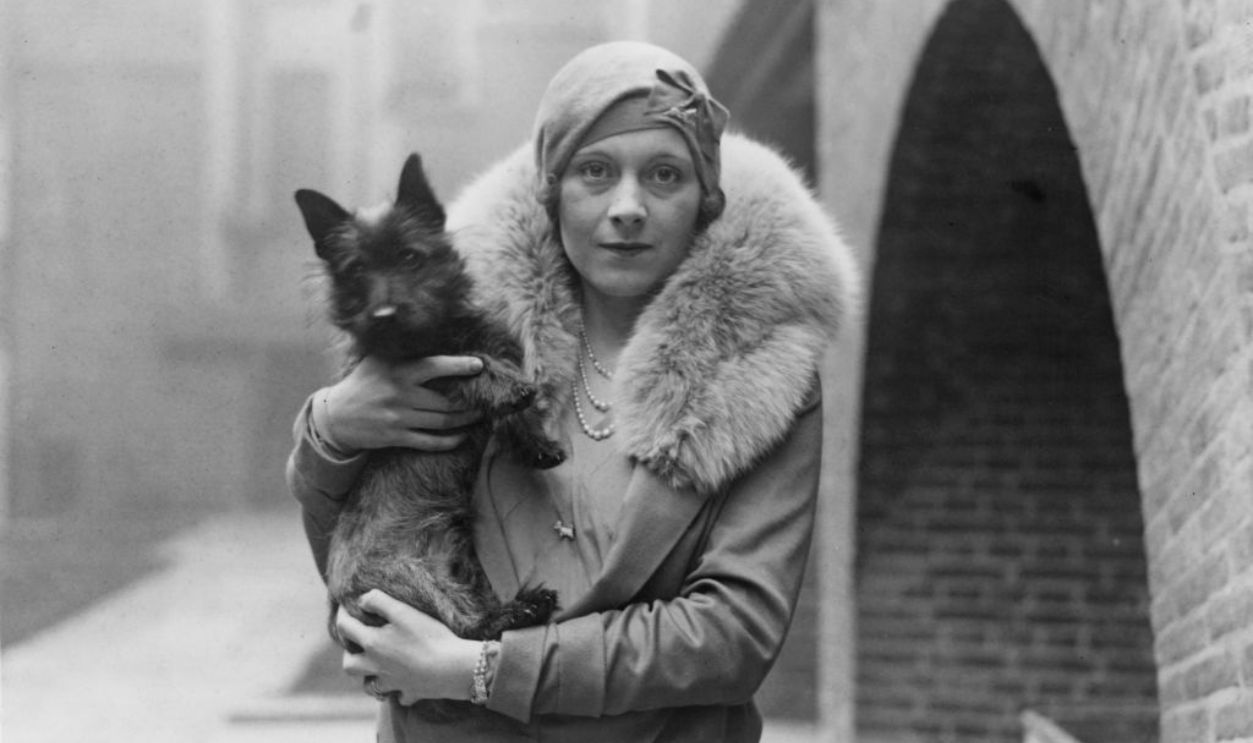 English author Barbara Cartland (1901 - 2000), the wife of Alexander McCorquodale, with her dog, December 1928. 