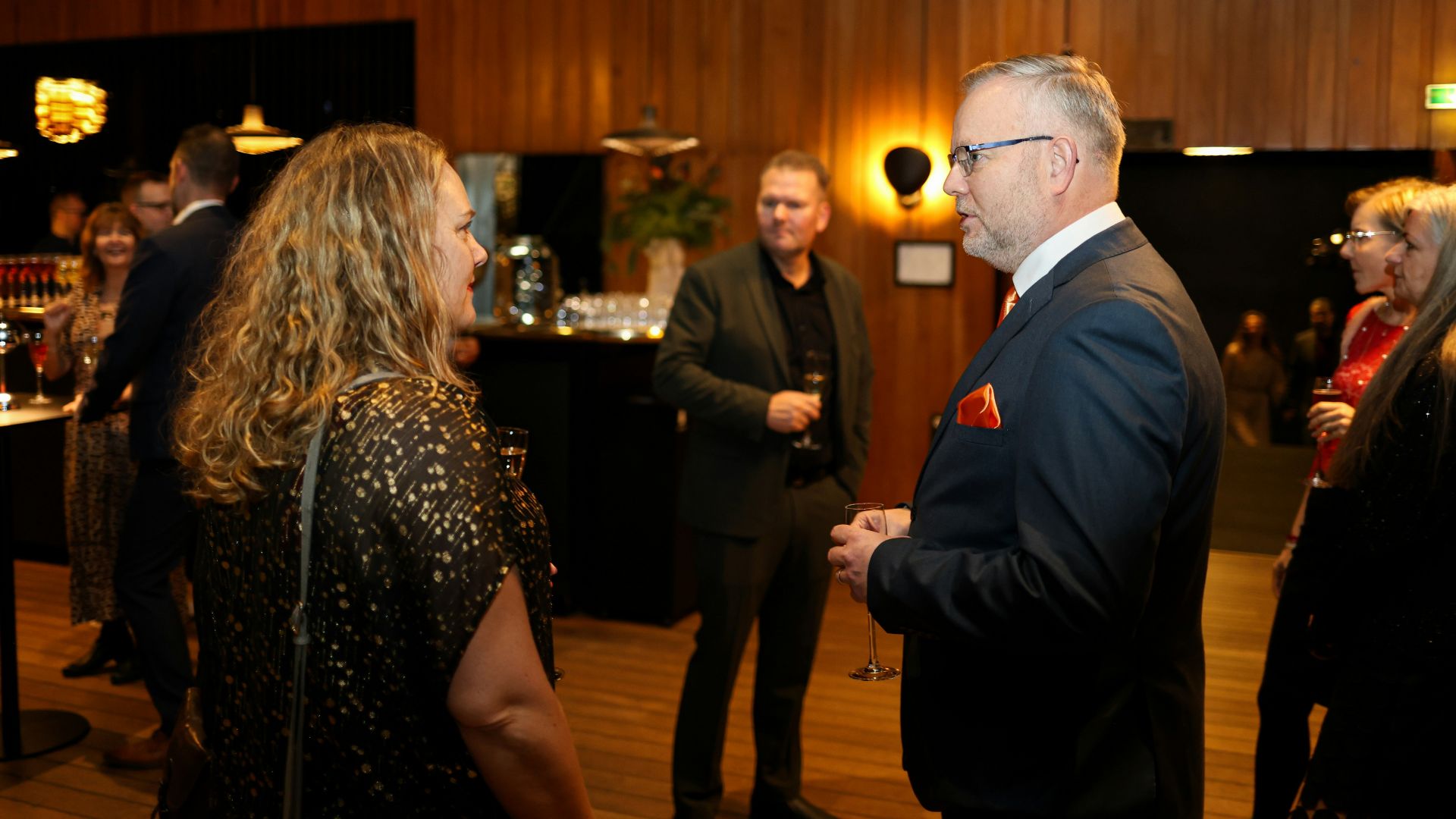 People mingling at a formal event with drinks