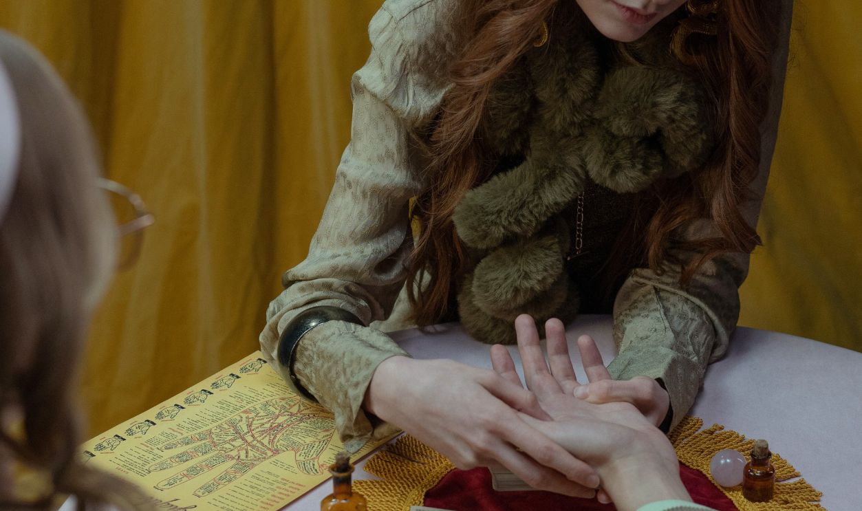 A fortune teller reads a palm surrounded by tarot cards, evoking a mystical atmosphere