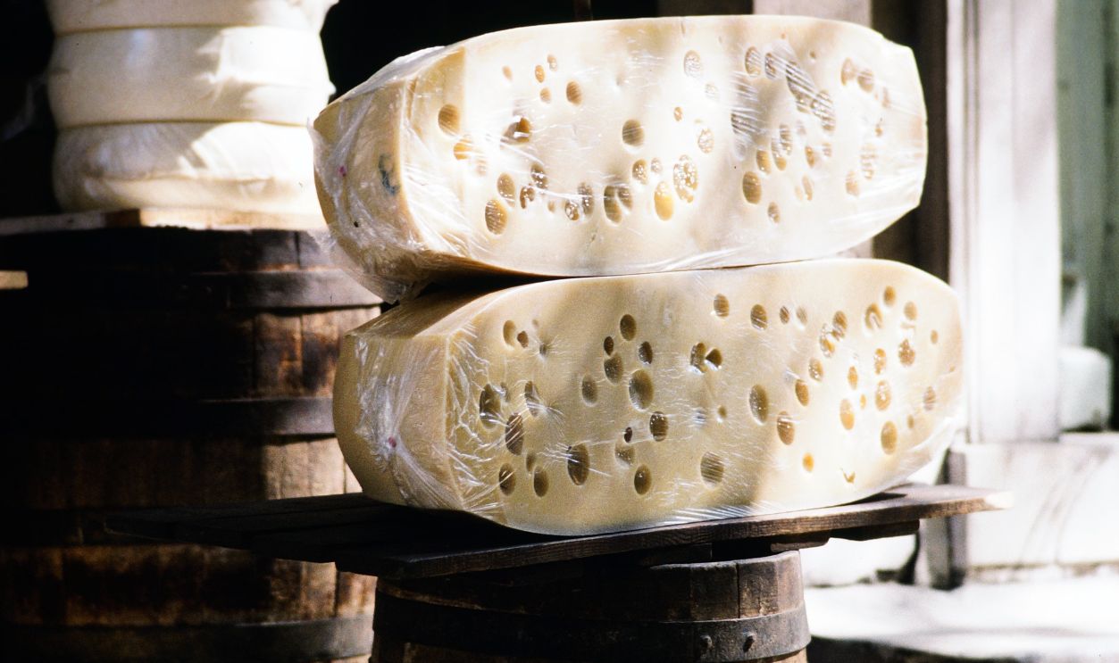Authentic Greek cheese wheels stacked outside a rustic shop in Greece, highlighting local culinary delights