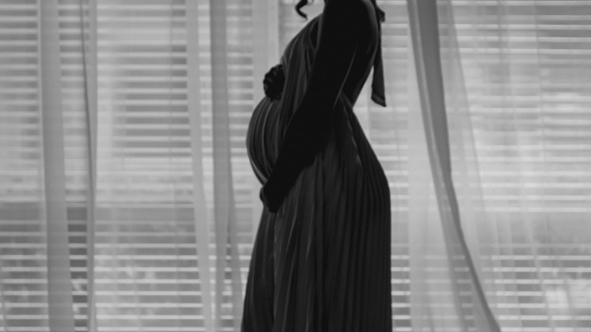 A pregnant woman standing in front of a window