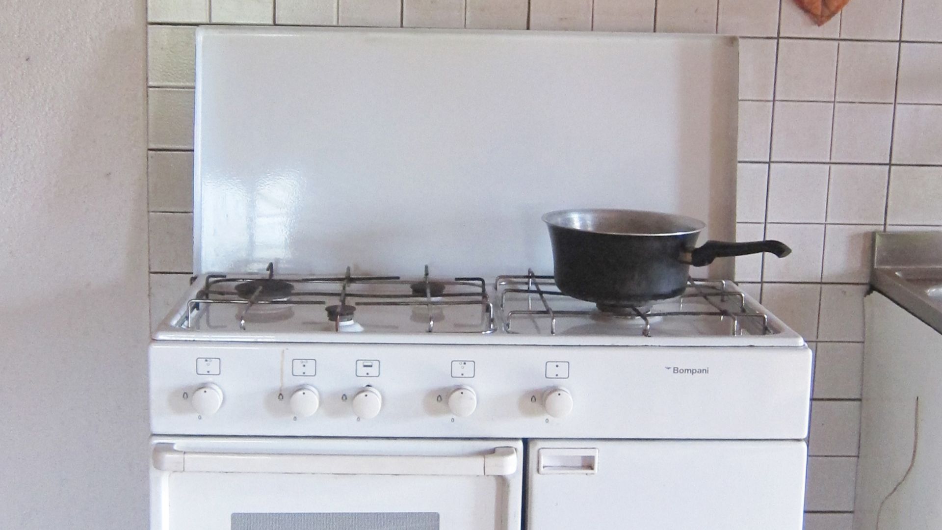 Picture of the gas kitchen stove in the main room of the bivouac hut Bivacco Primalpia. In this room you can find a row of triple bunk beds, dinner table, gas kitchen stove, wooden stove and kitchen, water sink and a fireplace. The bivouac, built in 1995,