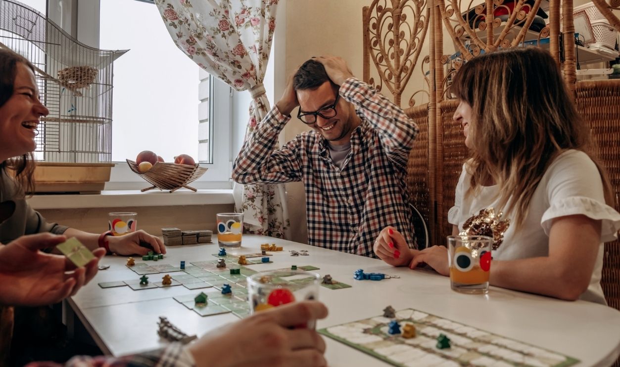 A group of young people play board games at home in the kitchen.Time together.Stay home,board games concept.Selective focus.