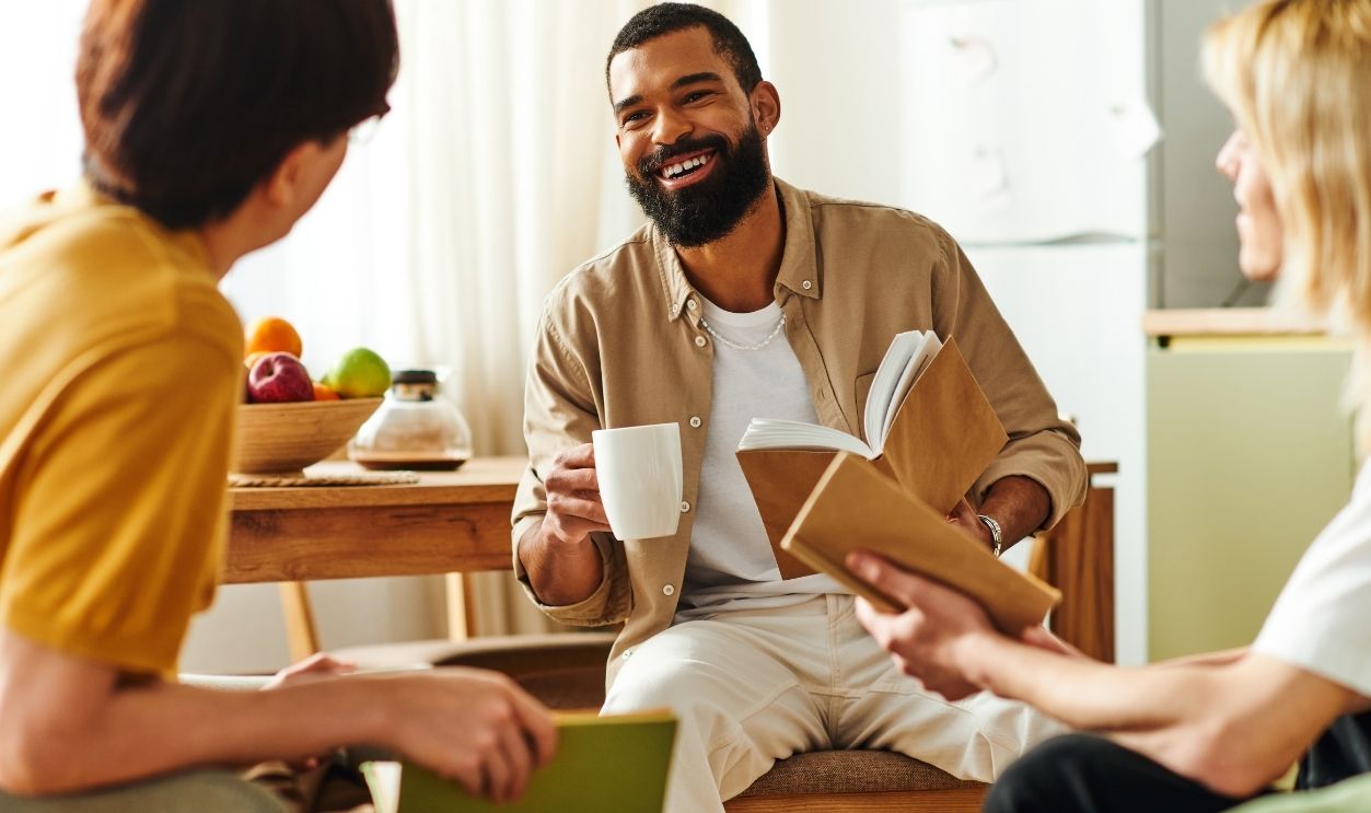 Young men gather in a stylish home setting to share insights over books and coffee.