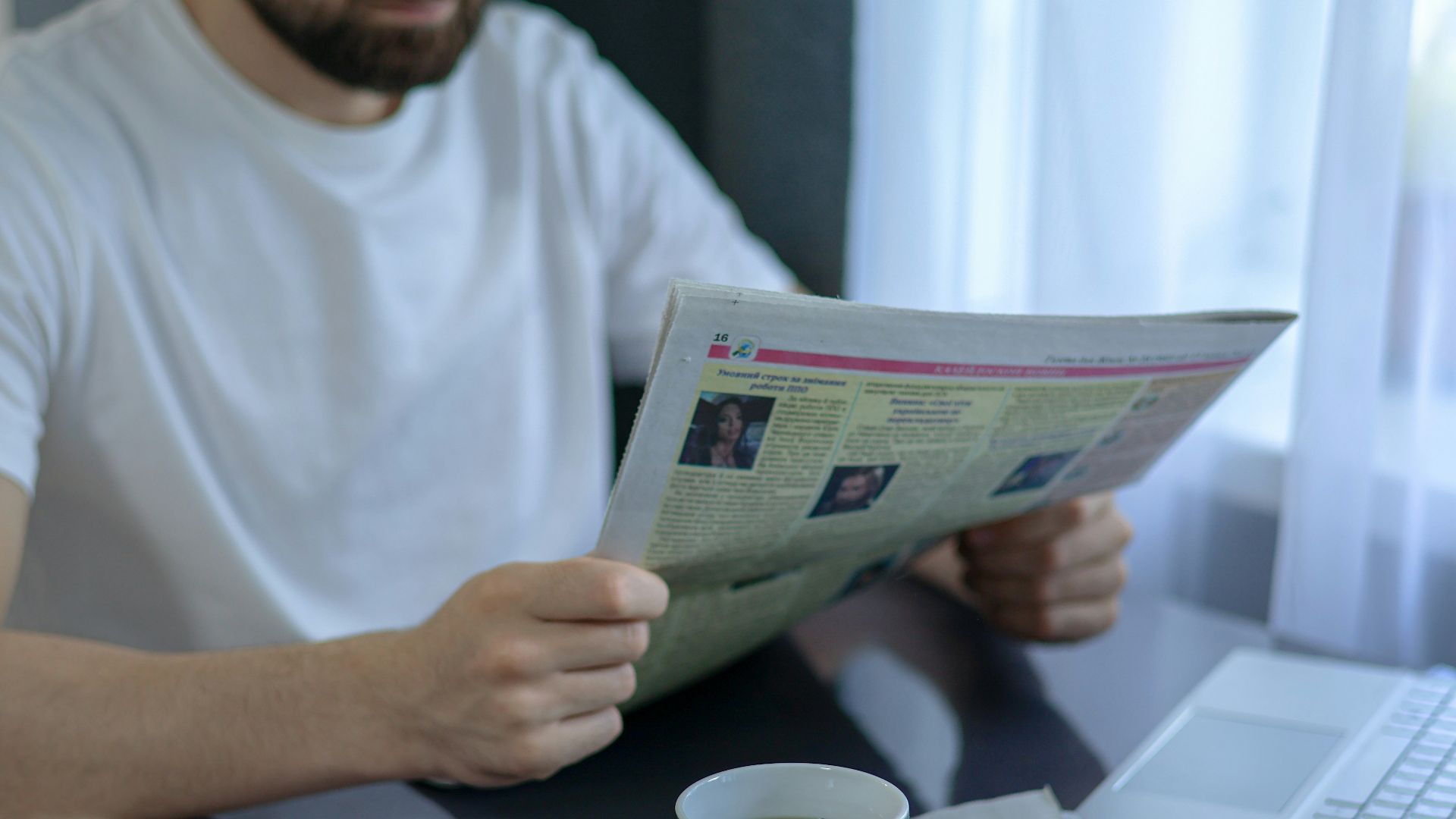 a man sitting at a table reading a newspaper
