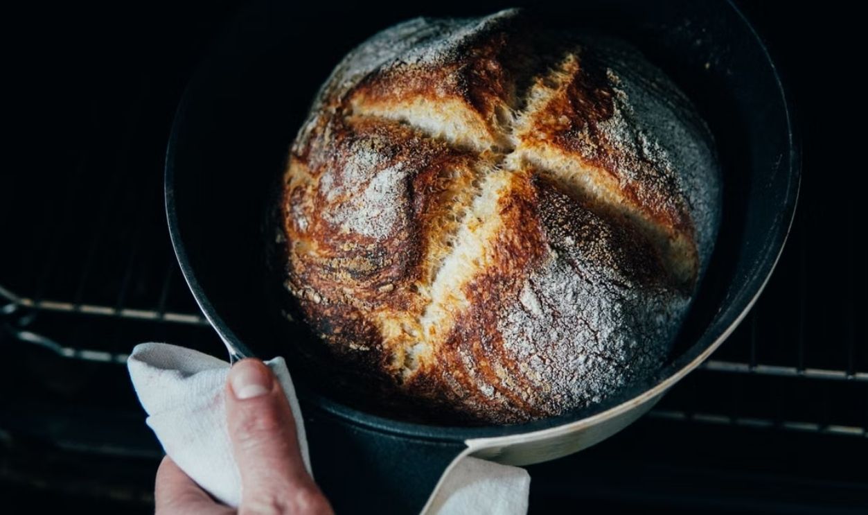 A close-up of rustic sourdough bread in a baking dish, fresh from the oven