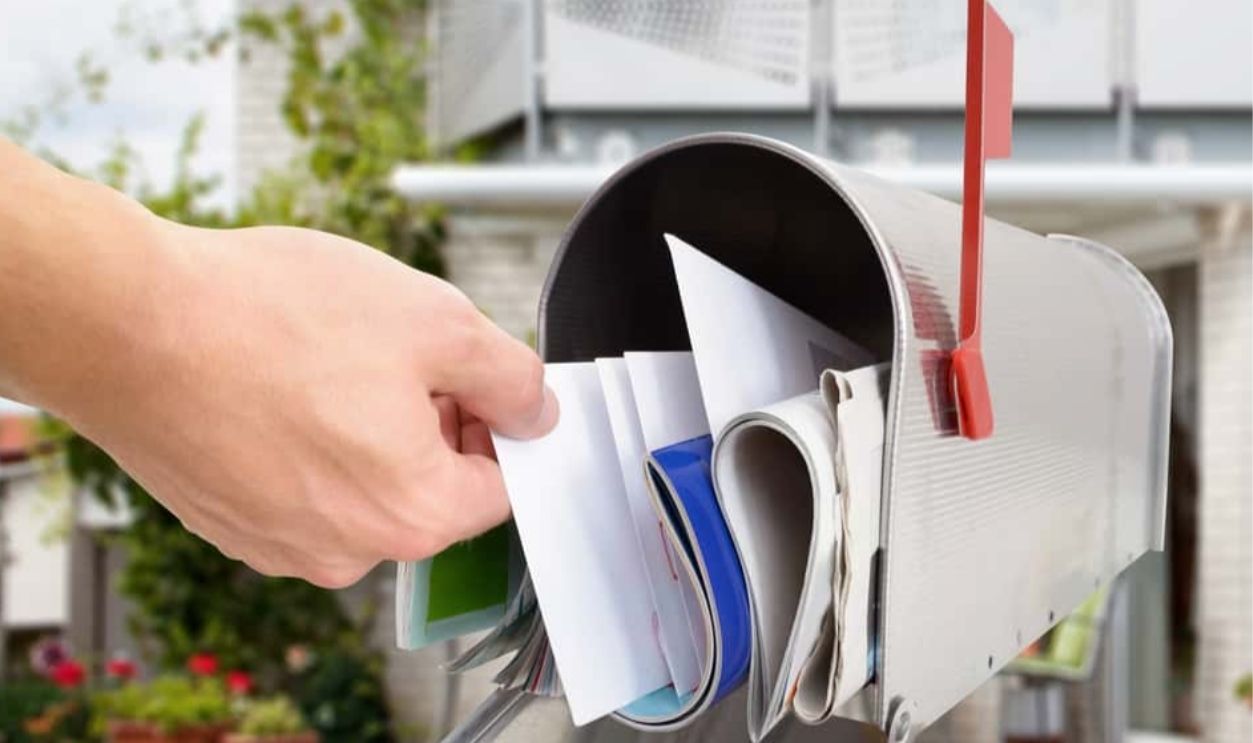 Close-up Of Man's Hand Taking Letter From Mailbox Outside House