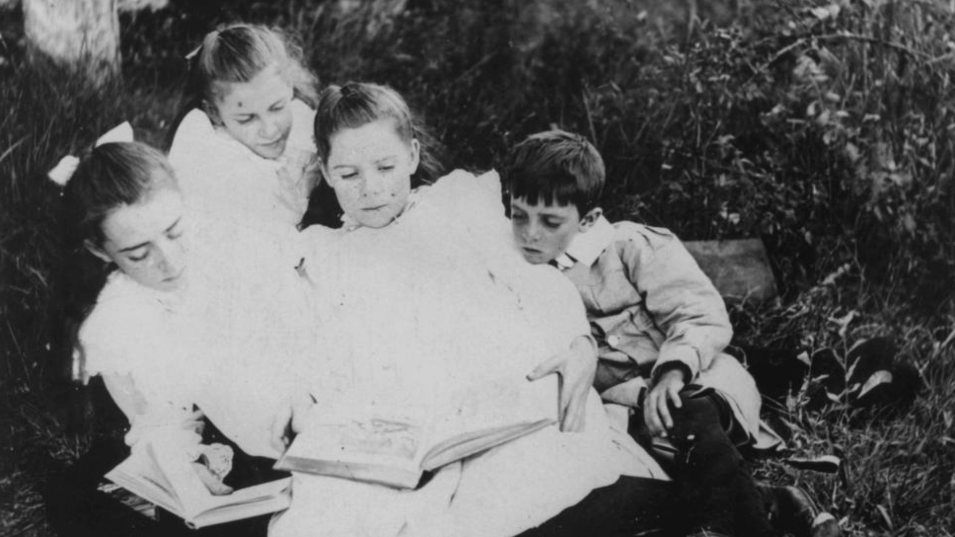 Group of children sitting on the grass reading books, 1900-1910
Portrait of a group of children sitting on the grass reading some books, 1900-1910. Two girls hold books. A boy and a girl look over the shoulder of one of them at a large, illustrated book.