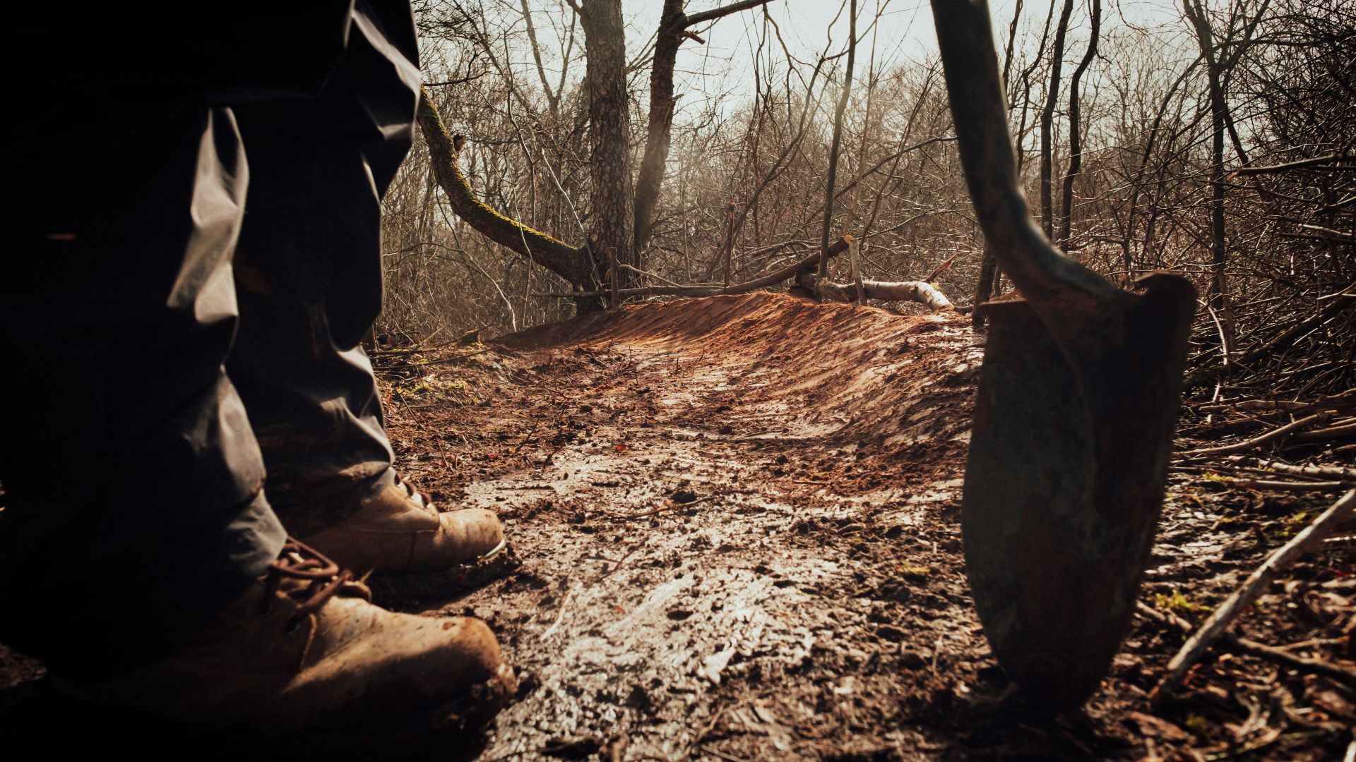 person in brown pants and brown boots holding brown wooden stick