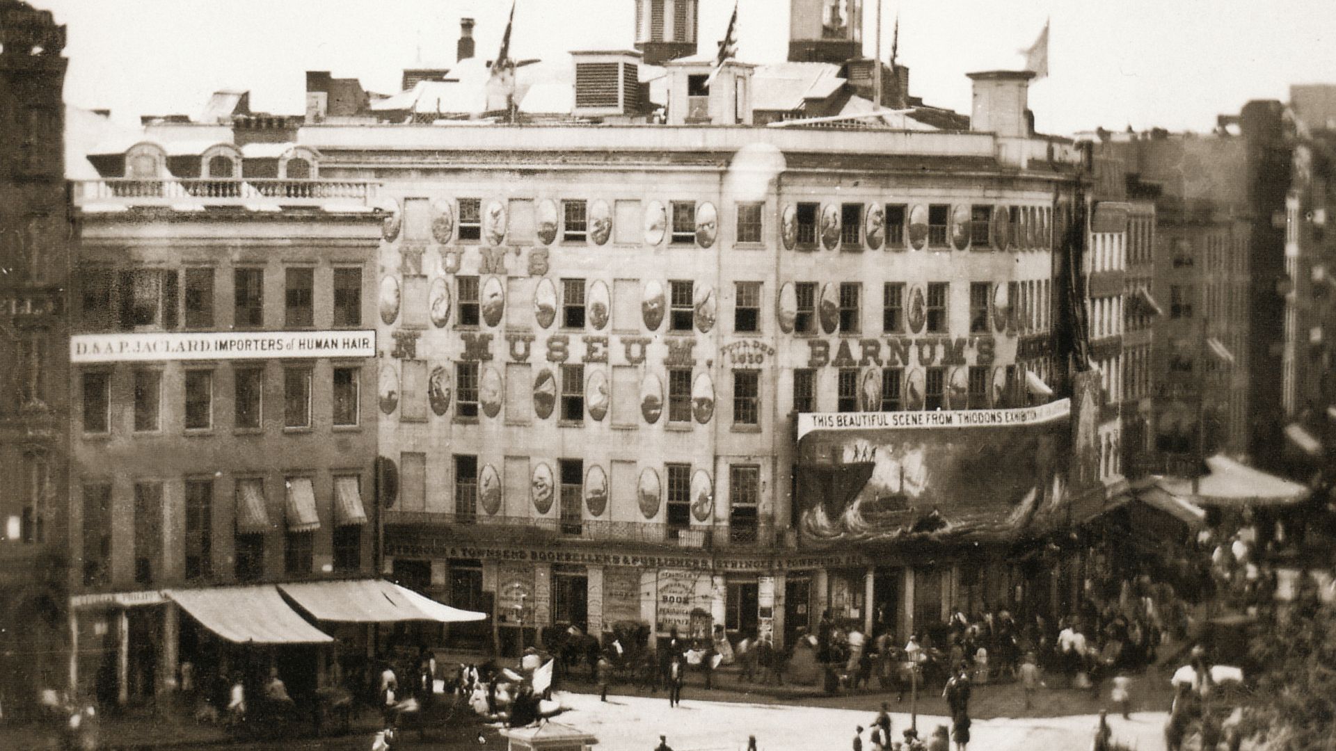 Barnum's American Museum in New York City. Left of the museum is a building with a sign that reads