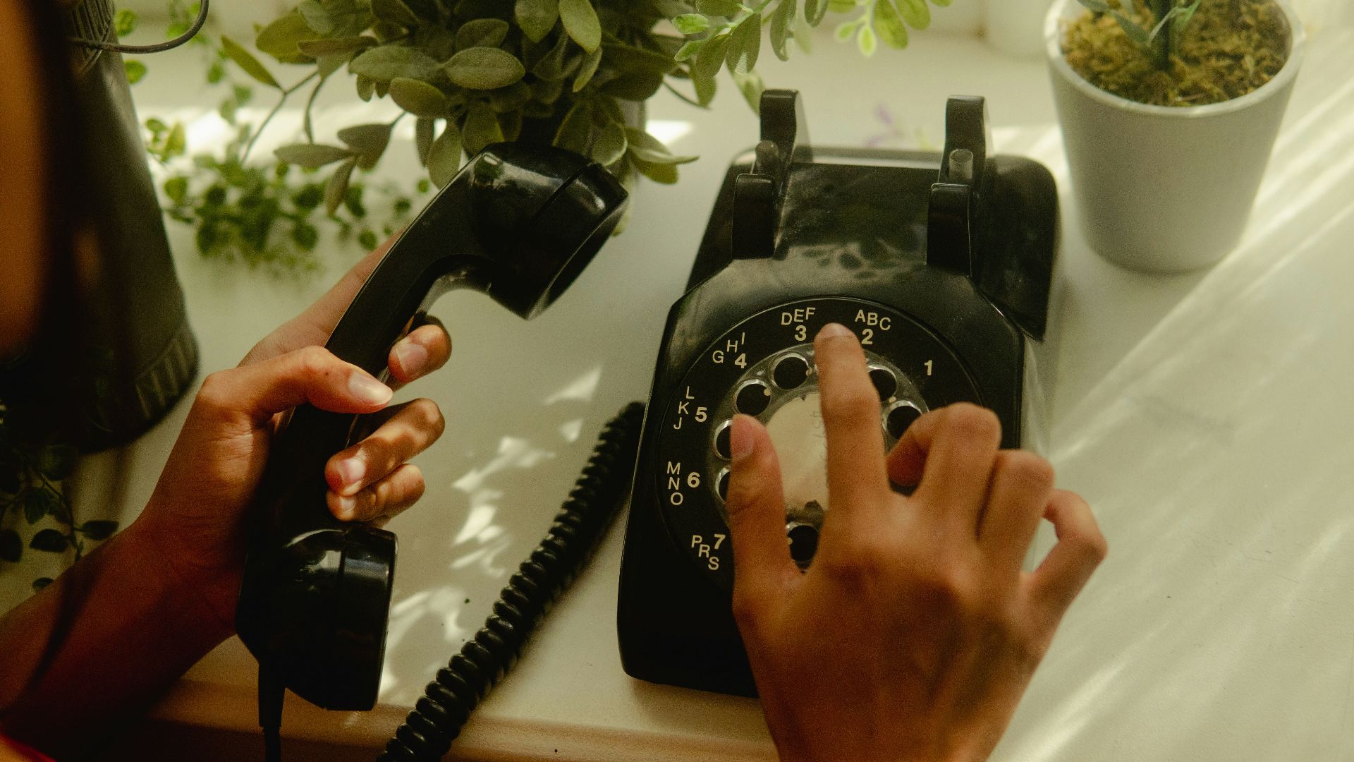 person holding black rotary telephone