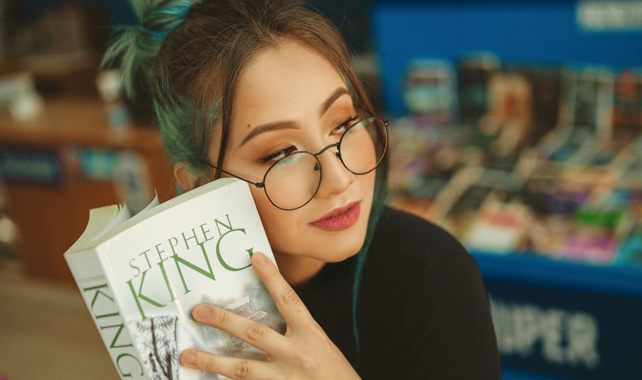Stylish young woman enjoying a Stephen King novel in a bookstore setting