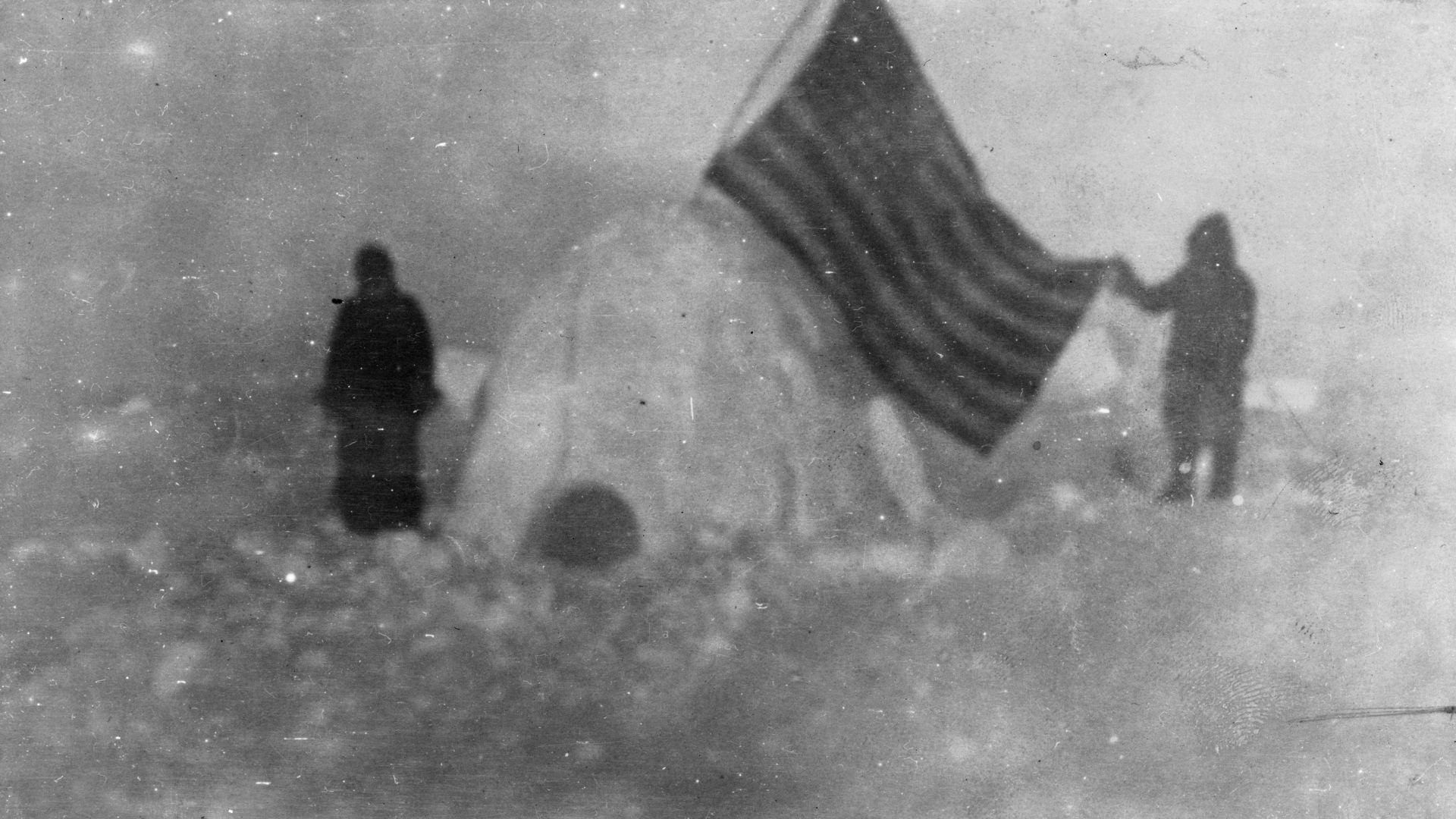 A photo of Frederick Cook's 1909 arctic expedition. Cook alleged that this photo was take near the North Pole. From that page: TITLE:  Two members of Frederick Cook's expedition, with U.S. flag stuck in igloo, at expedition camp site, North Pole CALL NUMB
