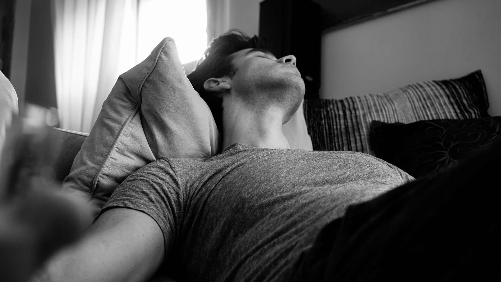 grayscale photo of man laying on bed