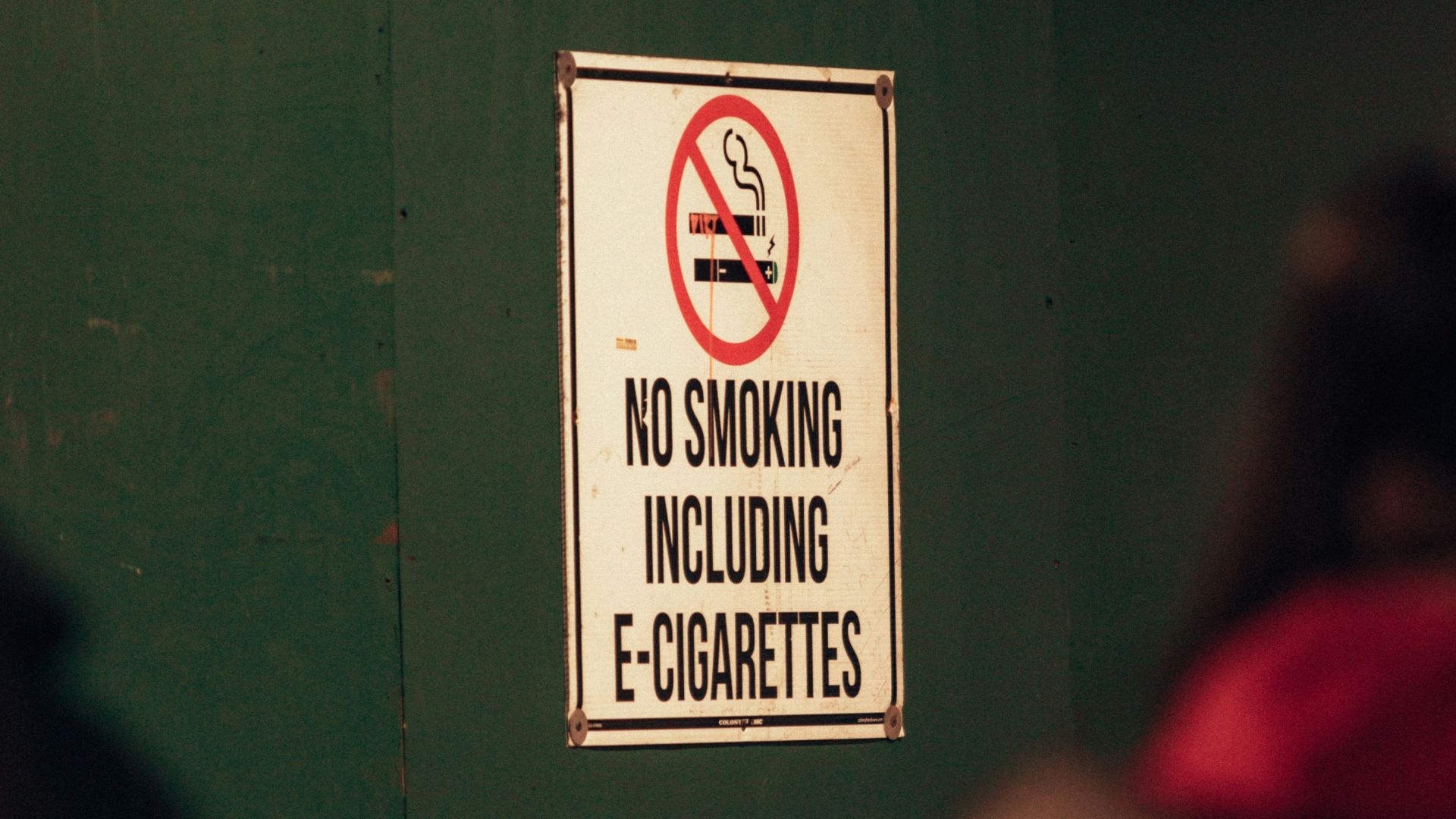 a no smoking sign on a green wall