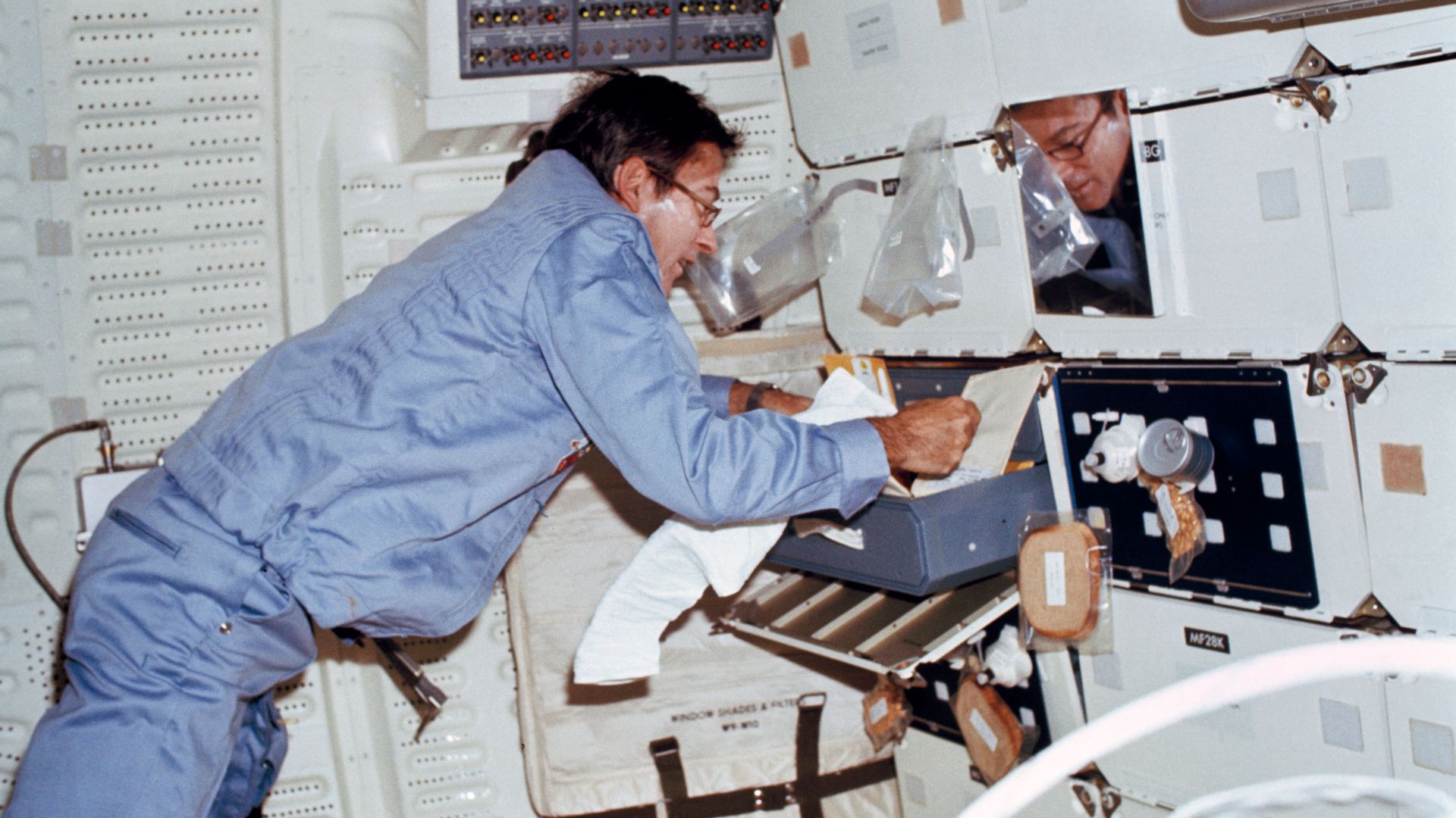 S81-30422 (12-14 April 1981) --- Astronaut John W. Young, STS-1 commander, cleans off his razor after shaving his face on the middeck of the space shuttle orbiter Columbia. A food tray can be seen mounted on a locker door at right. This 35mm frame was exp