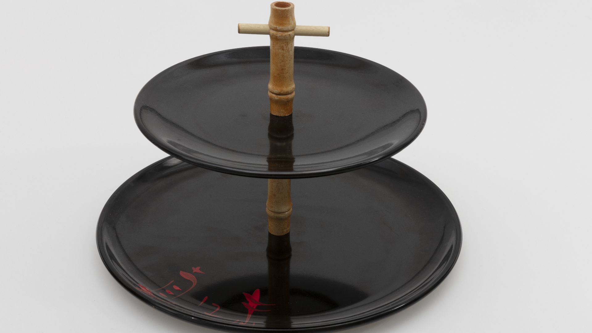 Ebonyte tiered serving tray in black. Ebonyte is LaMoyne's earliest known melamine dinnerware design and it dates from the late 1940s. The hand-painted characters on the cup were intended by the artist to translate to ?good taste.?