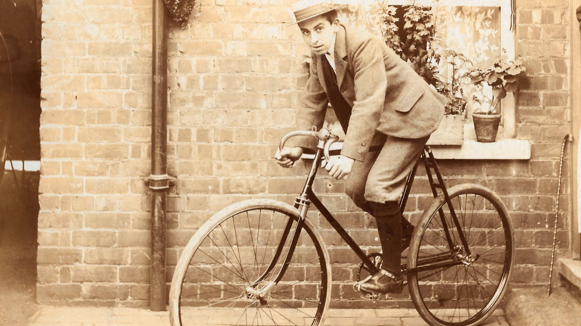 To me this has all the hallmarks of a young lad getting his first new bike, in the back yard of their house, with mum looking proudly on!
I'd love to know more about the bike. The image looks to be early 1900s and it has pneumatic tyres, fixed wheel with 