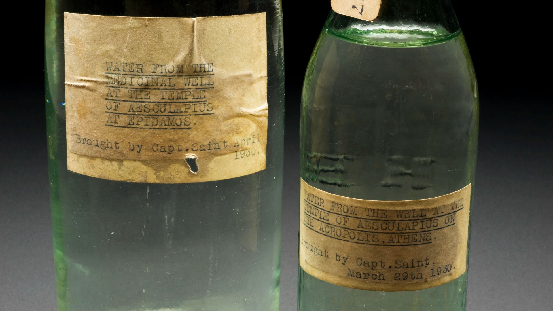 Left hand side - A79498, Bottle, originally for Evian water, containing water from the medicinal well of the temple of Aesculapius at Epidomos, Greece, collected in 1930. Right hand side - A79497, Bottle for medicinal water, with contents, from the well a