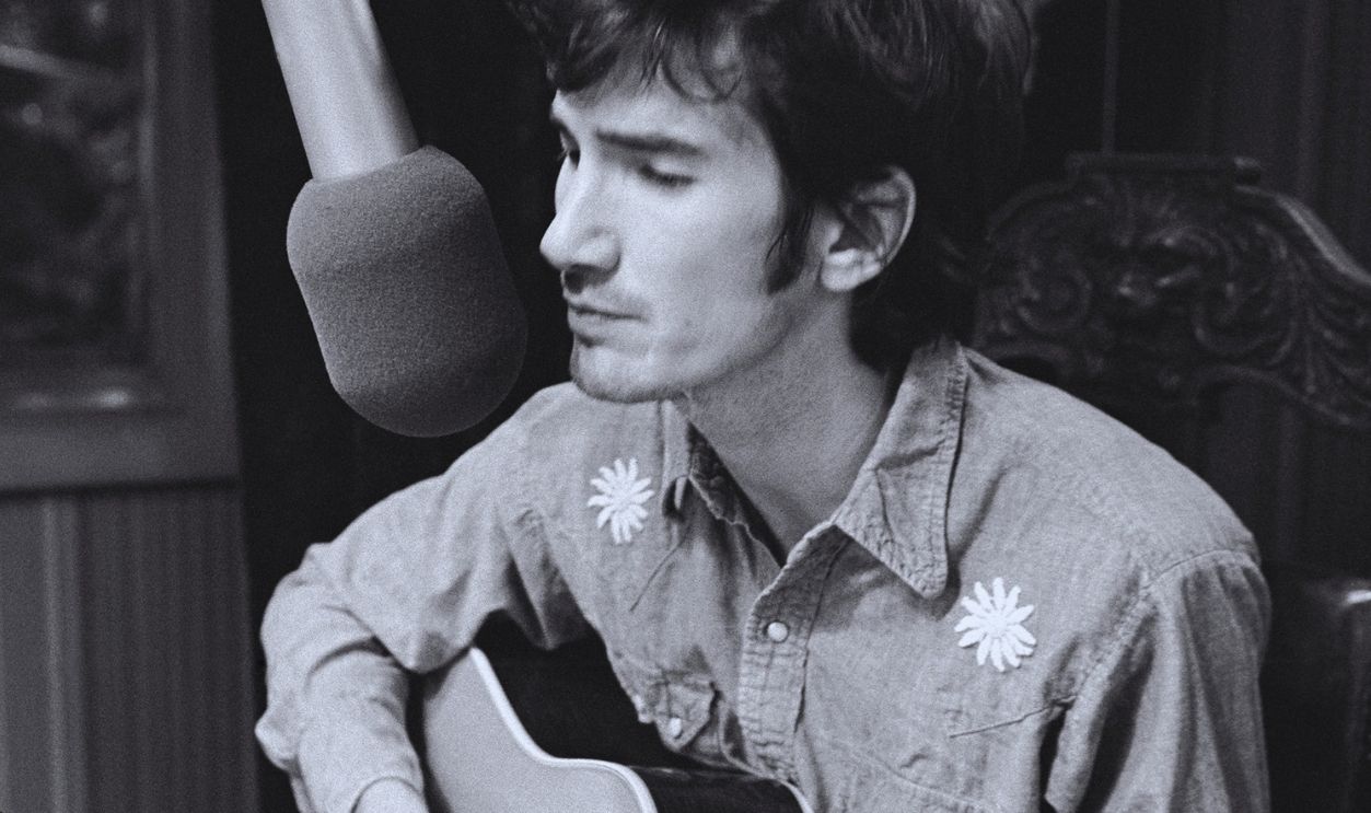 Singer, songwriter, musician Townes Van Zandt singing into a microphone and playing acoustic guitar at Jack Clement Recording Studios. Shot waist up in Nashville, Tennessee 1972. Photo is part of the Nashville Music Collection. 