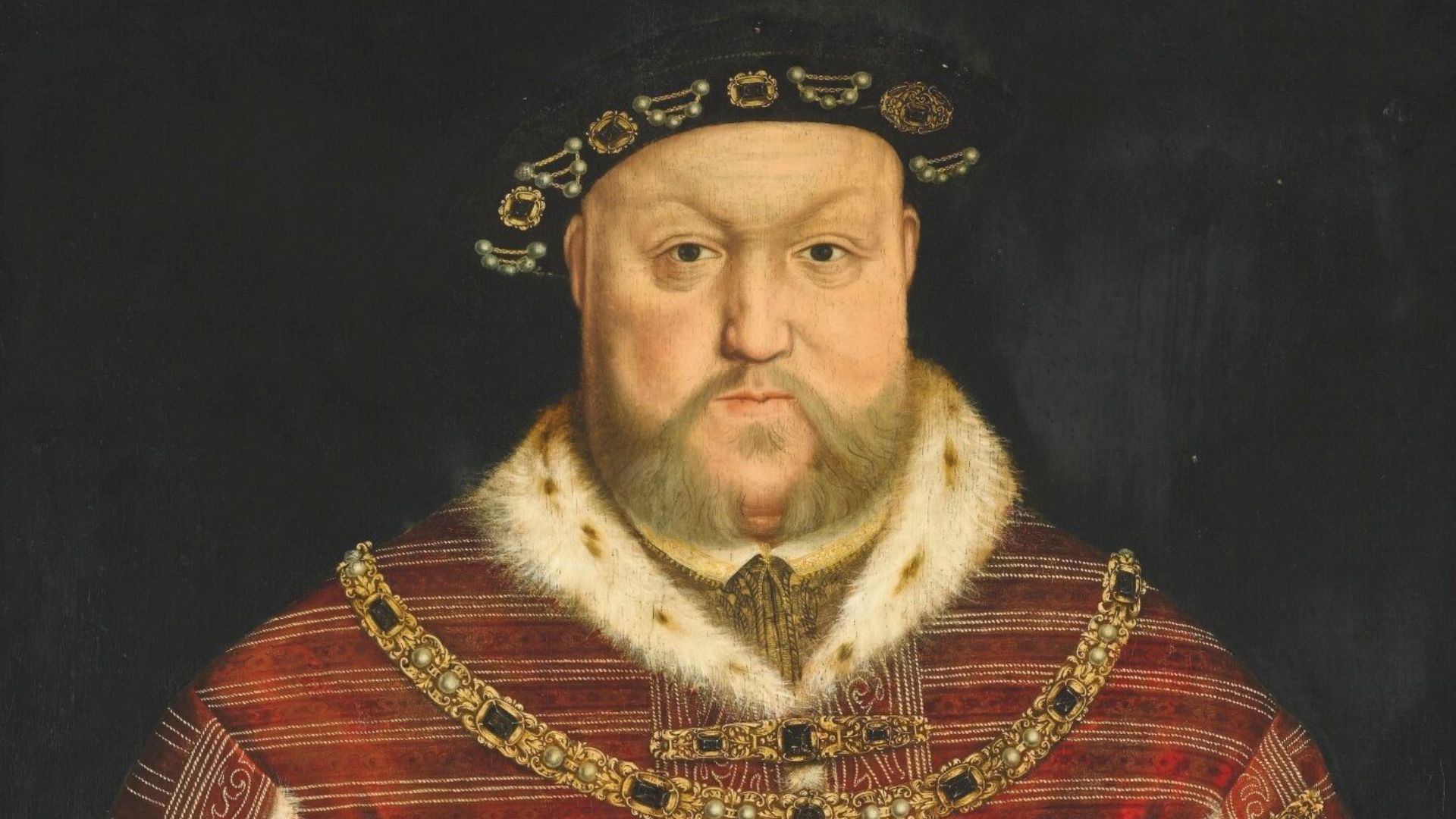 PORTRAIT OF KING HENRY VIII, HALF-LENGTH, WEARING A RICHLY EMBROIDERED RED VELVET SURCOAT, HOLDING A STAFF.
