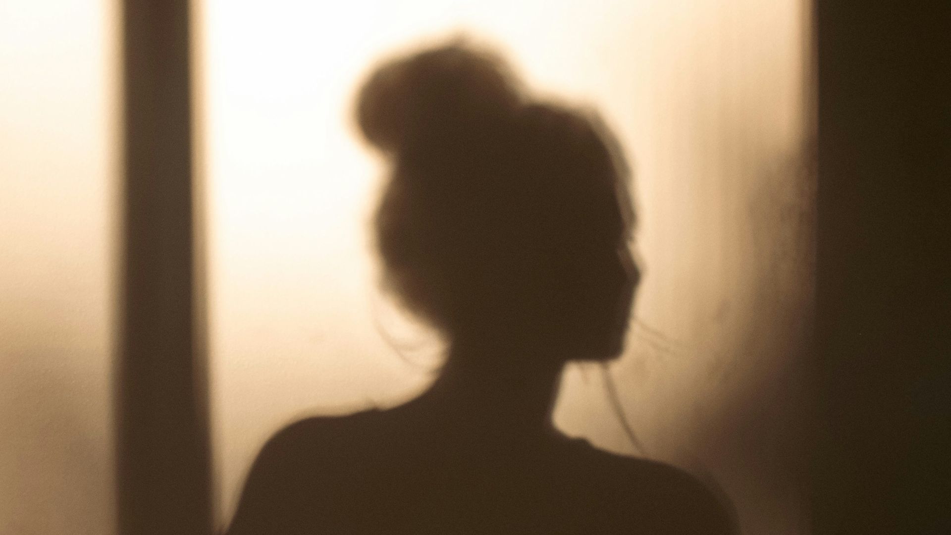 a shadow of a woman sitting on a bed
