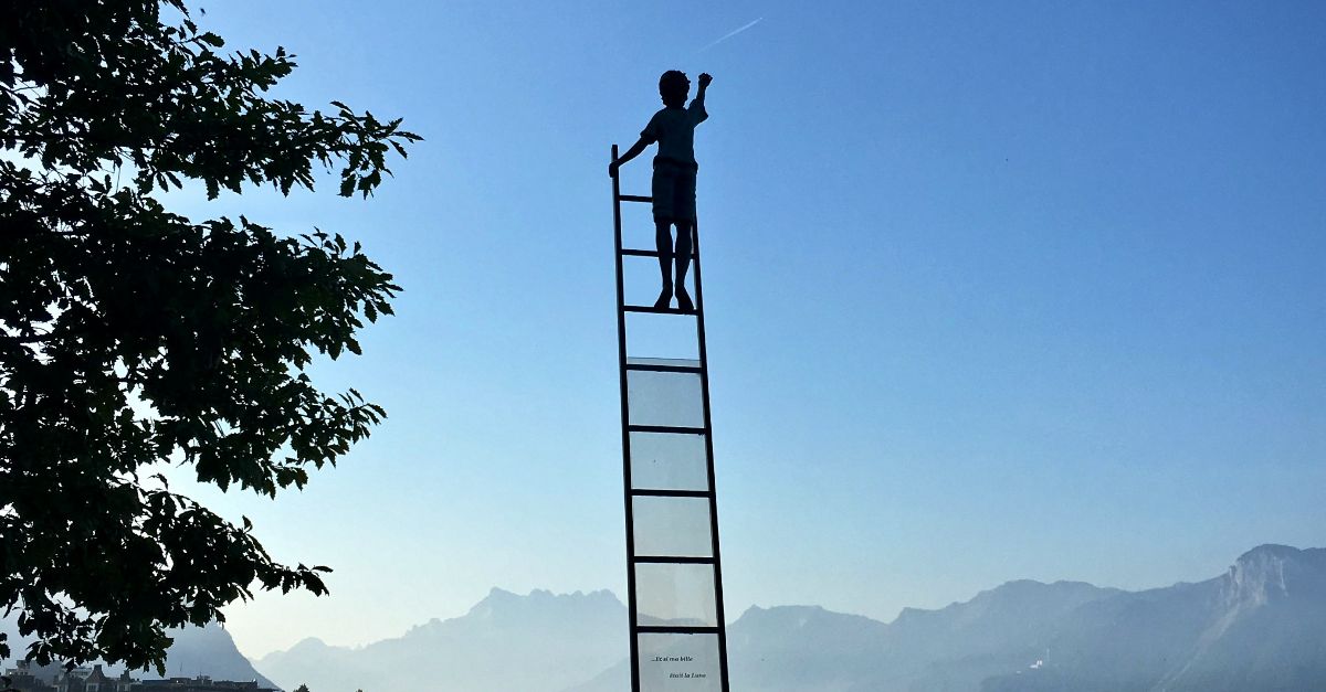 boy on ladder under blue sky