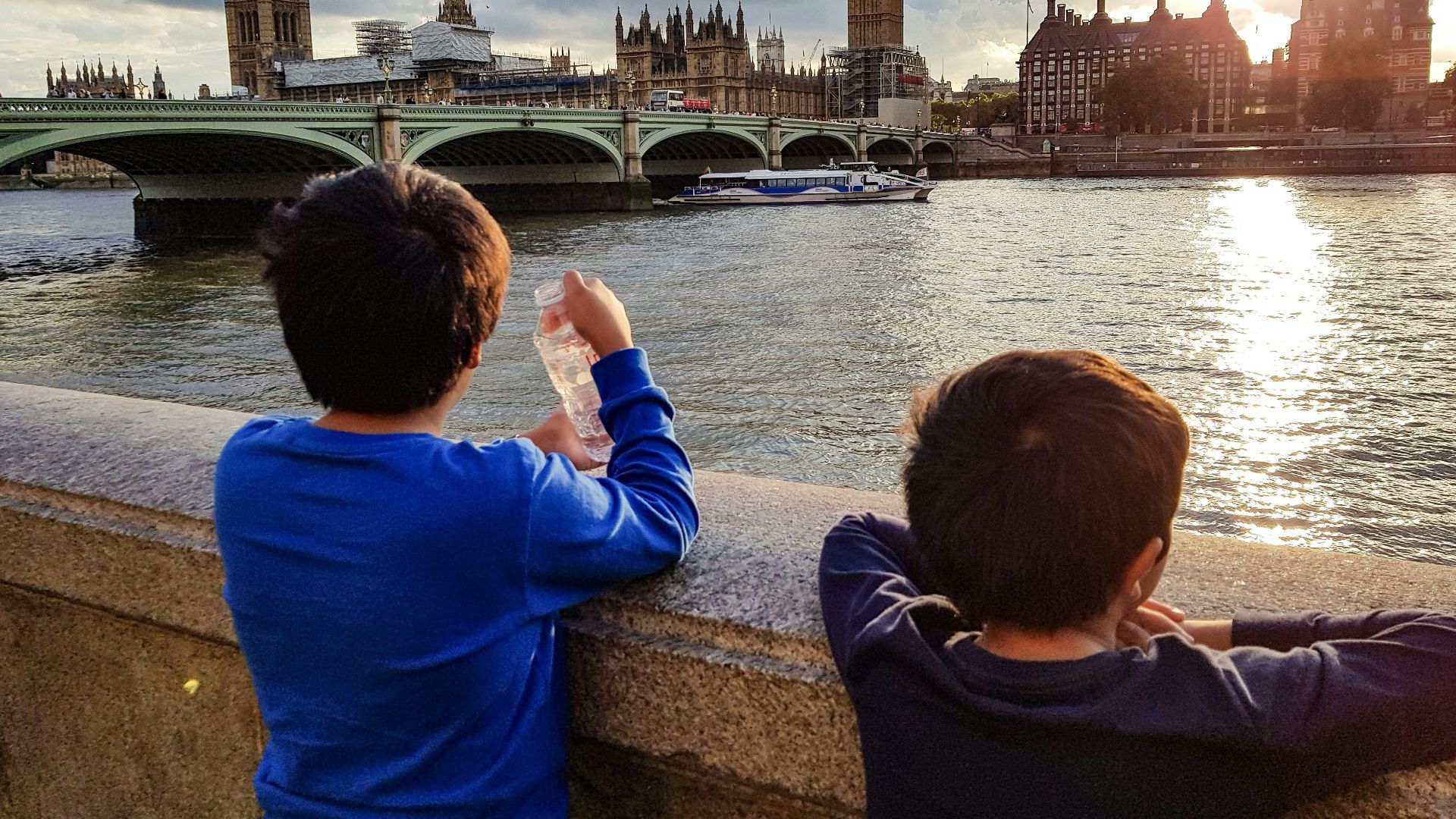 two boys watching golden hour near bridge