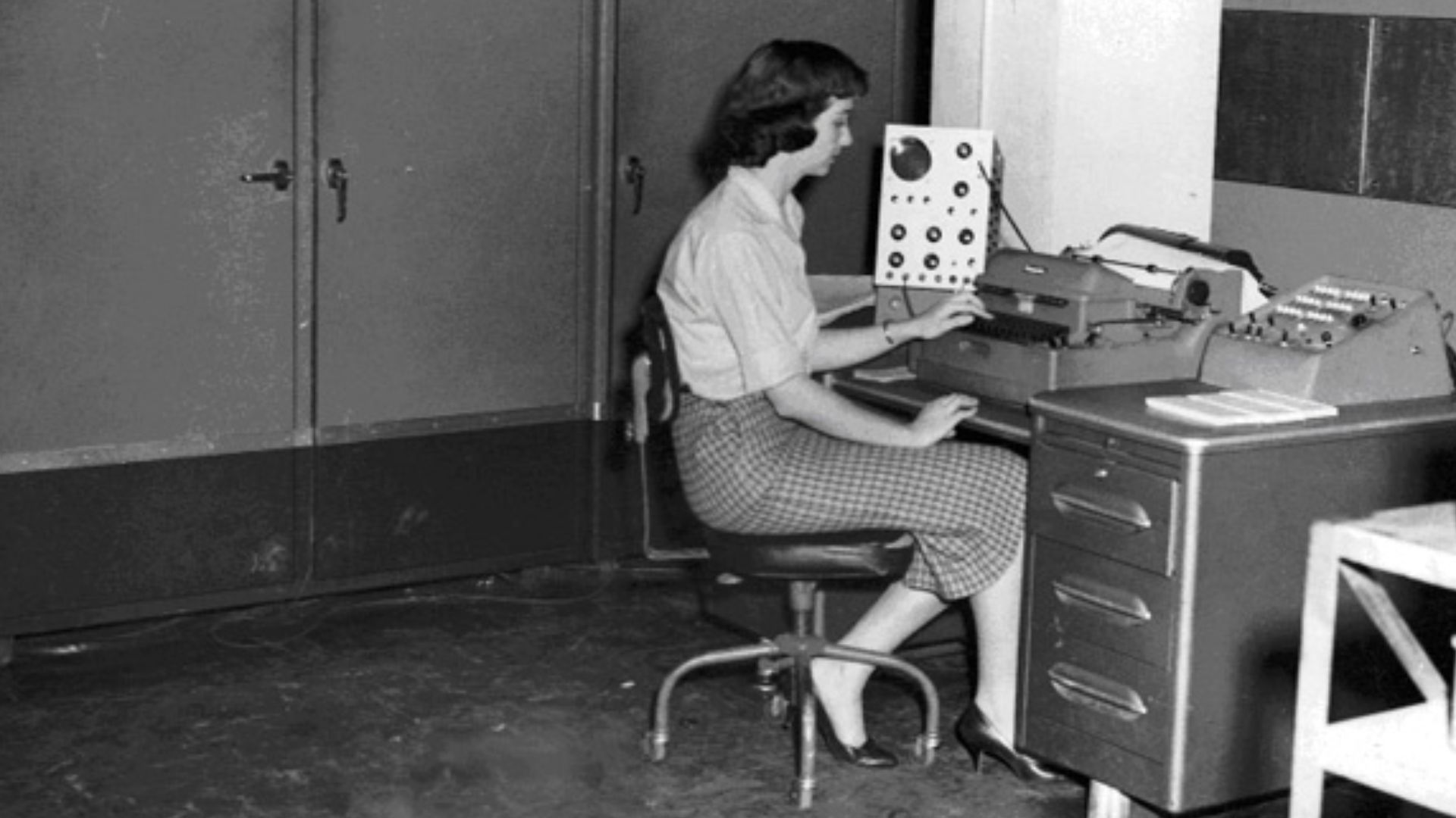 National Weather Records Center (NWRC) programmer Irma Lewis at the console of the ALWAC III computer in 1959. This early NWRC computer passed acceptance tests on July 1, 1955. It cost $85,000 and weighed 2,100 pounds (950 kg).