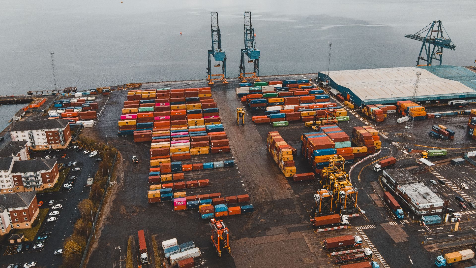 Aerial shot of a busy container port in Scotland with cranes and colorful cargo containers.