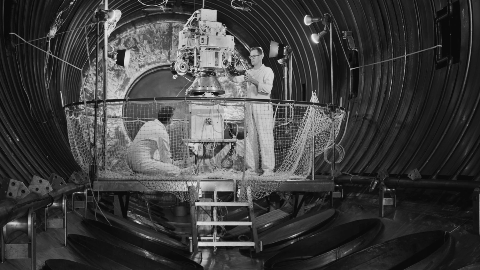 Technicians prepare the Space Electric Research Test (SERT-I) payload for a test in Tank Number 5 of the Electric Propulsion Laboratory at the National Aeronautics and Space Administration (NASA) Lewis Research Center. Lewis researchers had been studying 