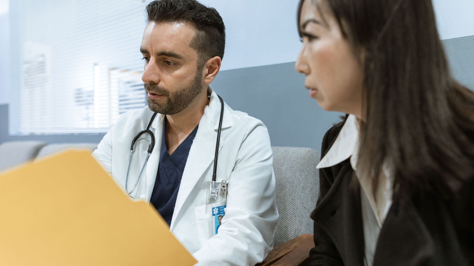 Doctor discusses health records with a patient in a clinical setting.