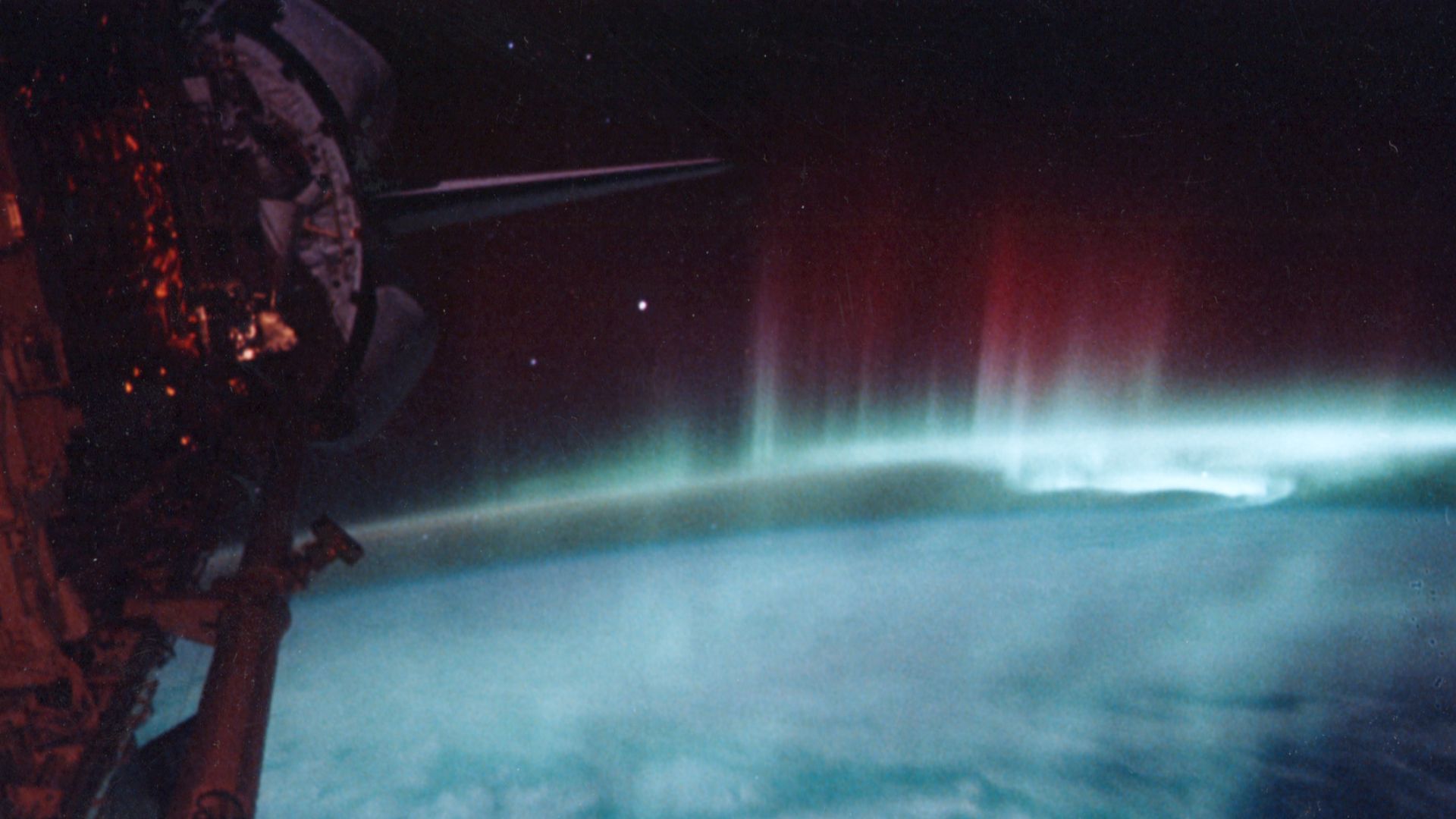 The Aurora Australis as seen from the Space Shuttle Discovery on STS-39. The payload bay and tail of Discovery can be seen on the left hand side of the picture. Auroras are caused when high-energy electrons pour down from the Earth’s magnetosphere and col