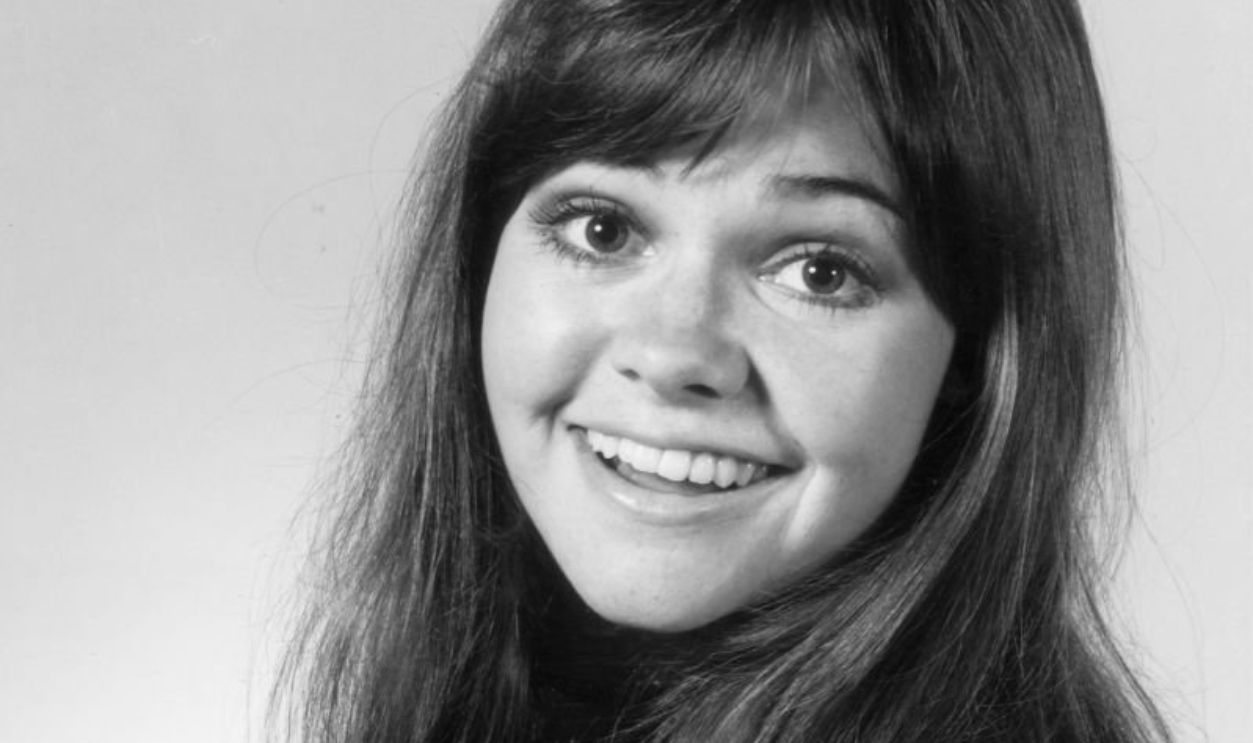 circa 1965: Studio headshot portrait of American actor Sally Field looking over shoulder and smiling. She wears her hair down.
