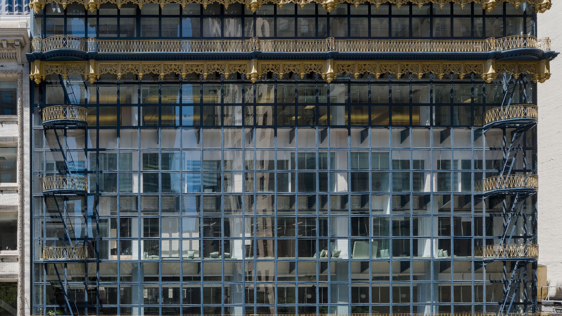 Hallidie Building (built 1917–1918), an early glass curtain‑wall office building designed by Willis Polk, on Sutter Street in the Financial District of San Francisco, California. Front elevation with gilded cornice, decorative iron balconies, external fir
