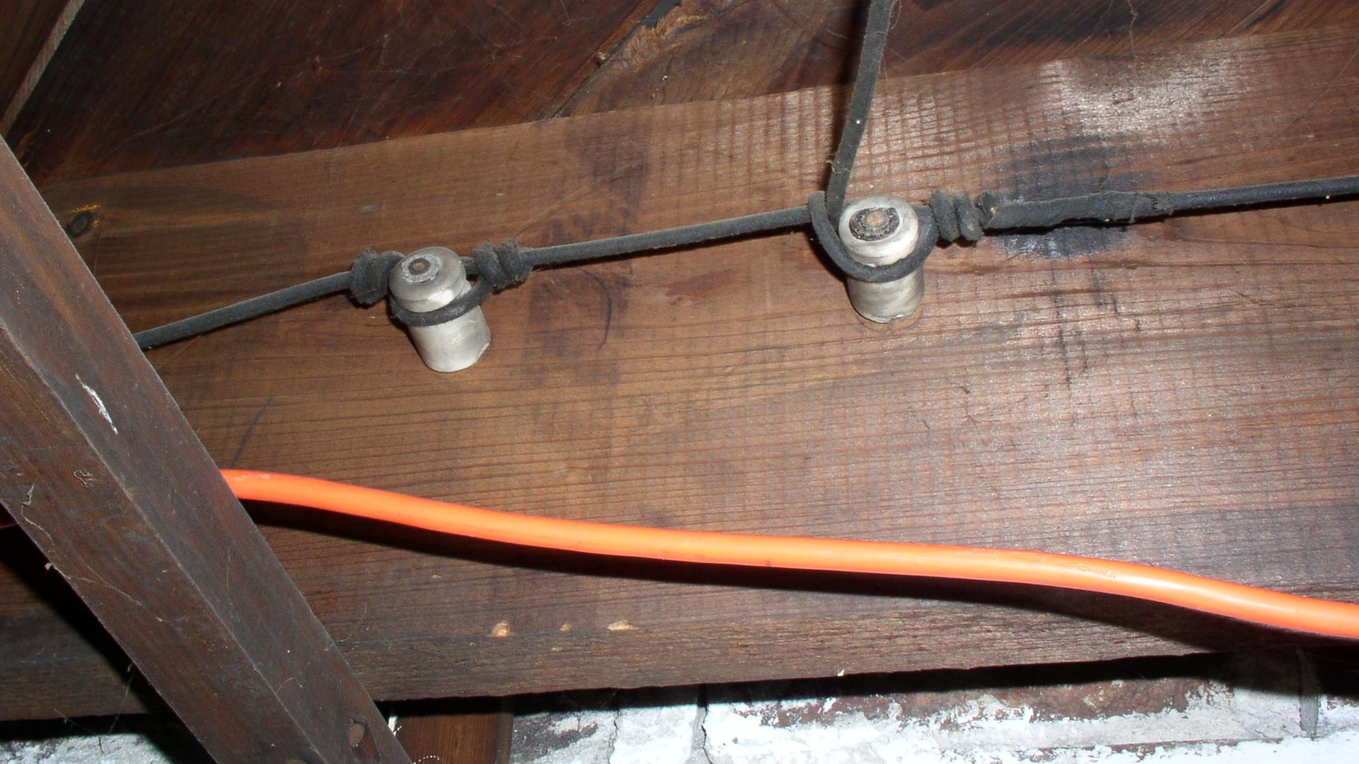 An example of early knob and tube wiring.  In some cases, a single knob could serve multiple functions: protecting a splice, supporting a run, and turning a corner.