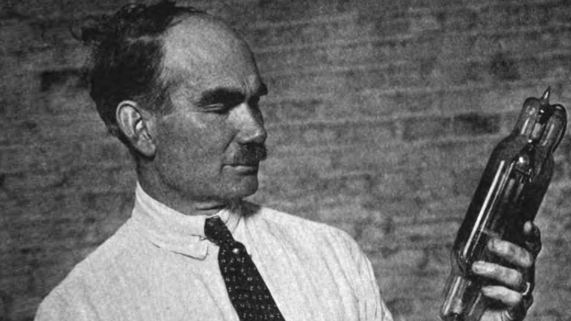 American electrical engineer Lee De Forest, the inventor of the triode vacuum tube, with two of his tubes.  De Forest's three electrode tube, which he invented in 1906 and called the