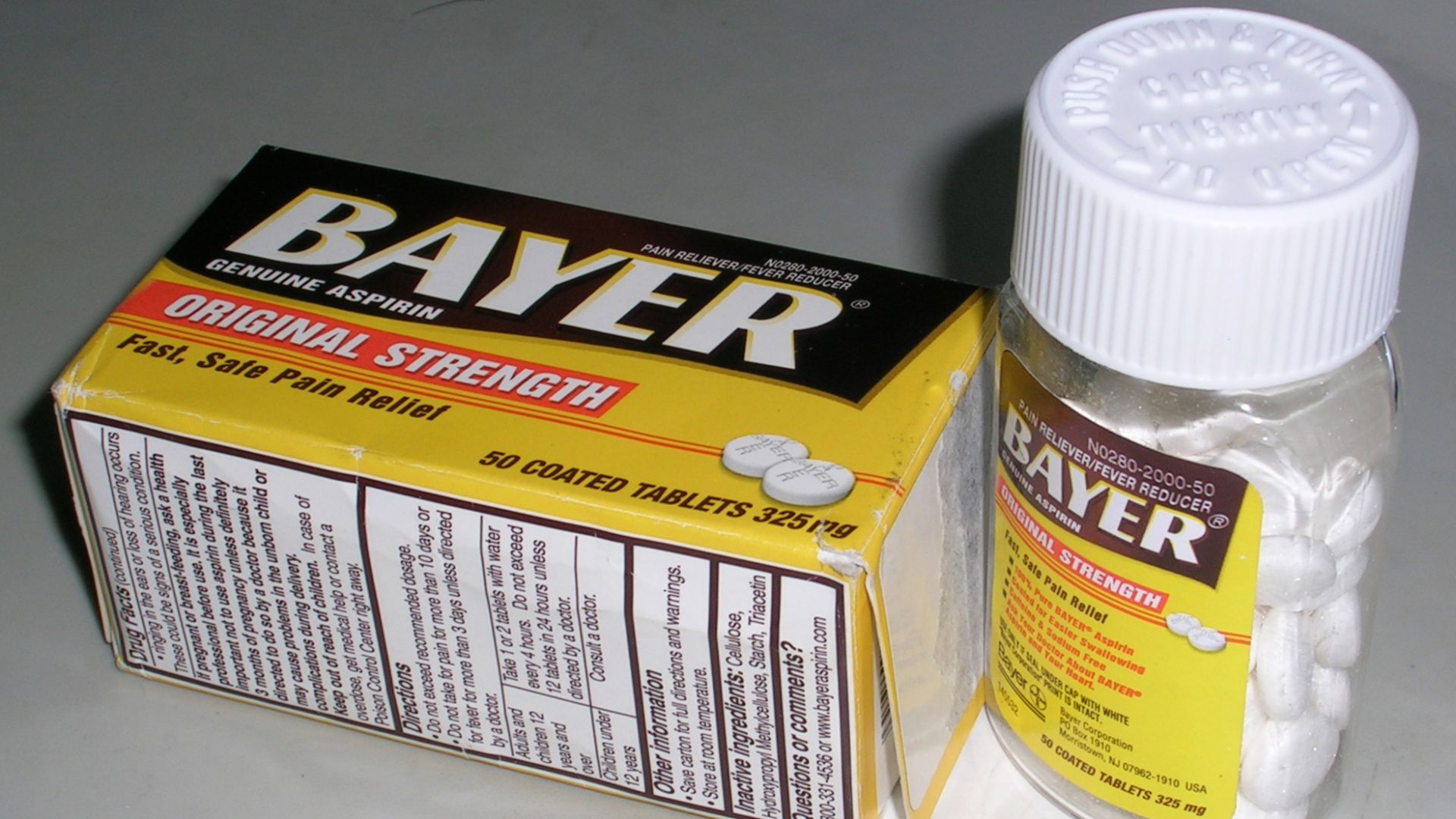 A bottle of Bayer brand coated aspirin tablets with a child-resistant cap bearing the instruction