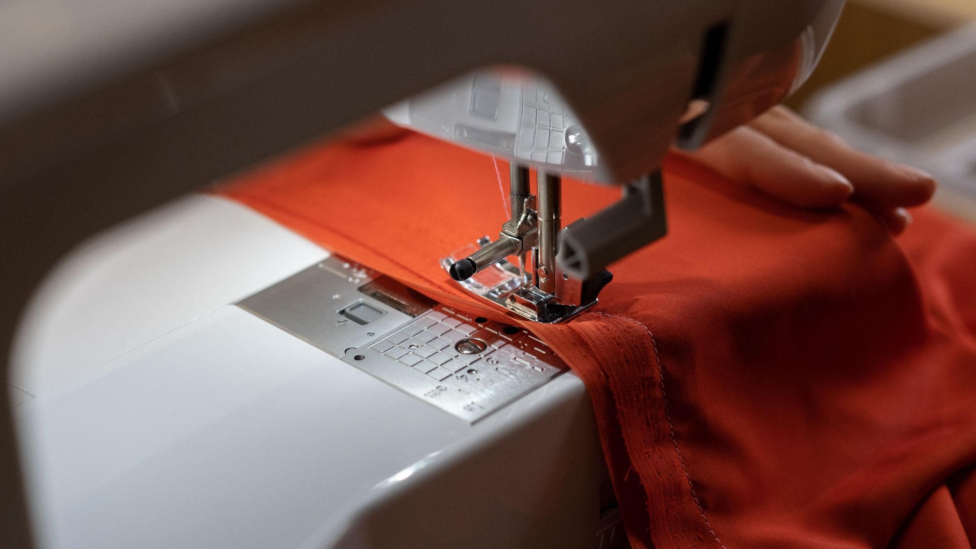 Close-up view of a sewing machine working on red fabric, representing craftsmanship.