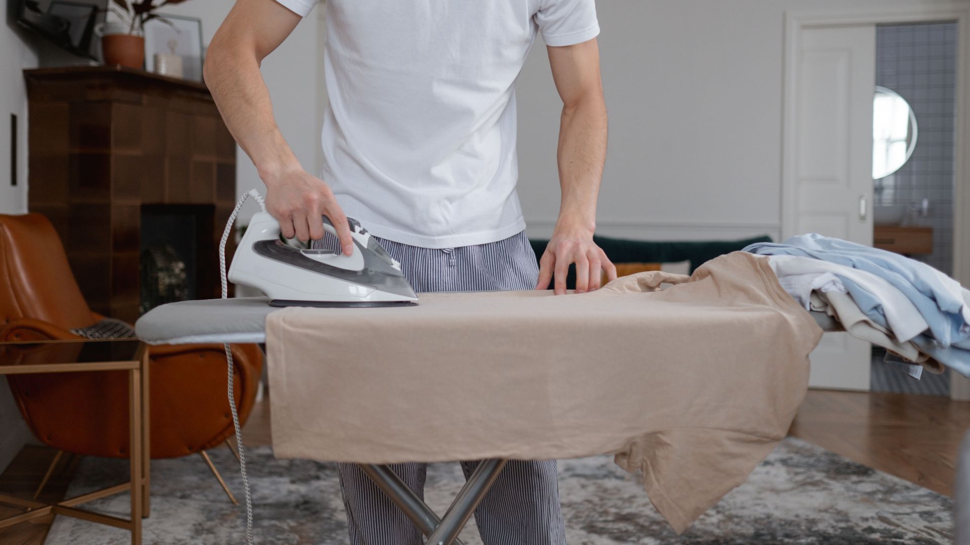 Man performing ironing chores in a modern home interior setting.