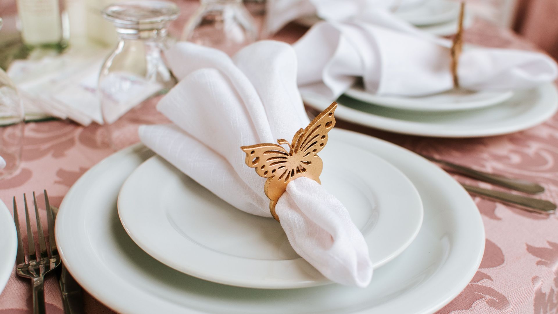 Sophisticated wedding table setting featuring butterfly napkin rings, fine china, and elegant tableware.