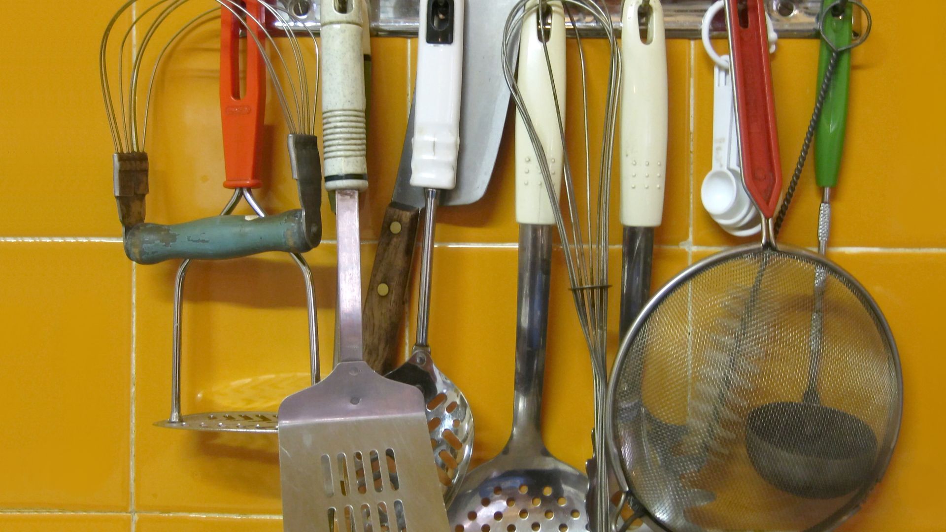 Kitchen tools, which mainly come from the 1970s, on a kitchen hook strip. From left:
Pastry blender and potato masher
Spatula and (hidden) serving fork
Skimmer and chef's knife (small cleaver)
Whisk and slotted spoon
Spaghetti ladle
Sieve and measuring sp